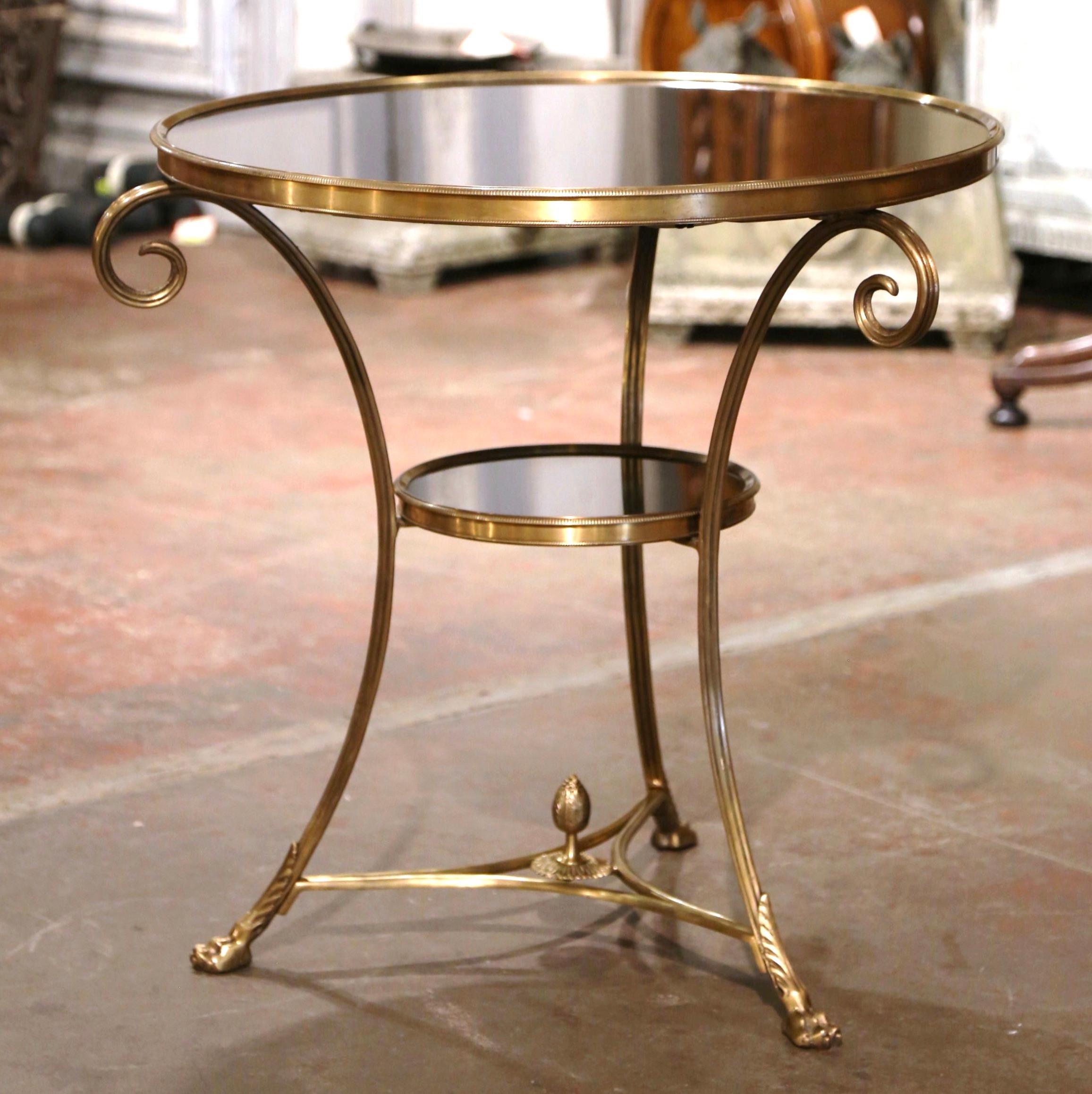 Decorate a living room with this elegant neoclassical antique two-tier gueridon table. Created in France circa 1950, and round in shape, the table is supported by three slender cabriole legs ending with hoof feet and decorated with acanthus leaf