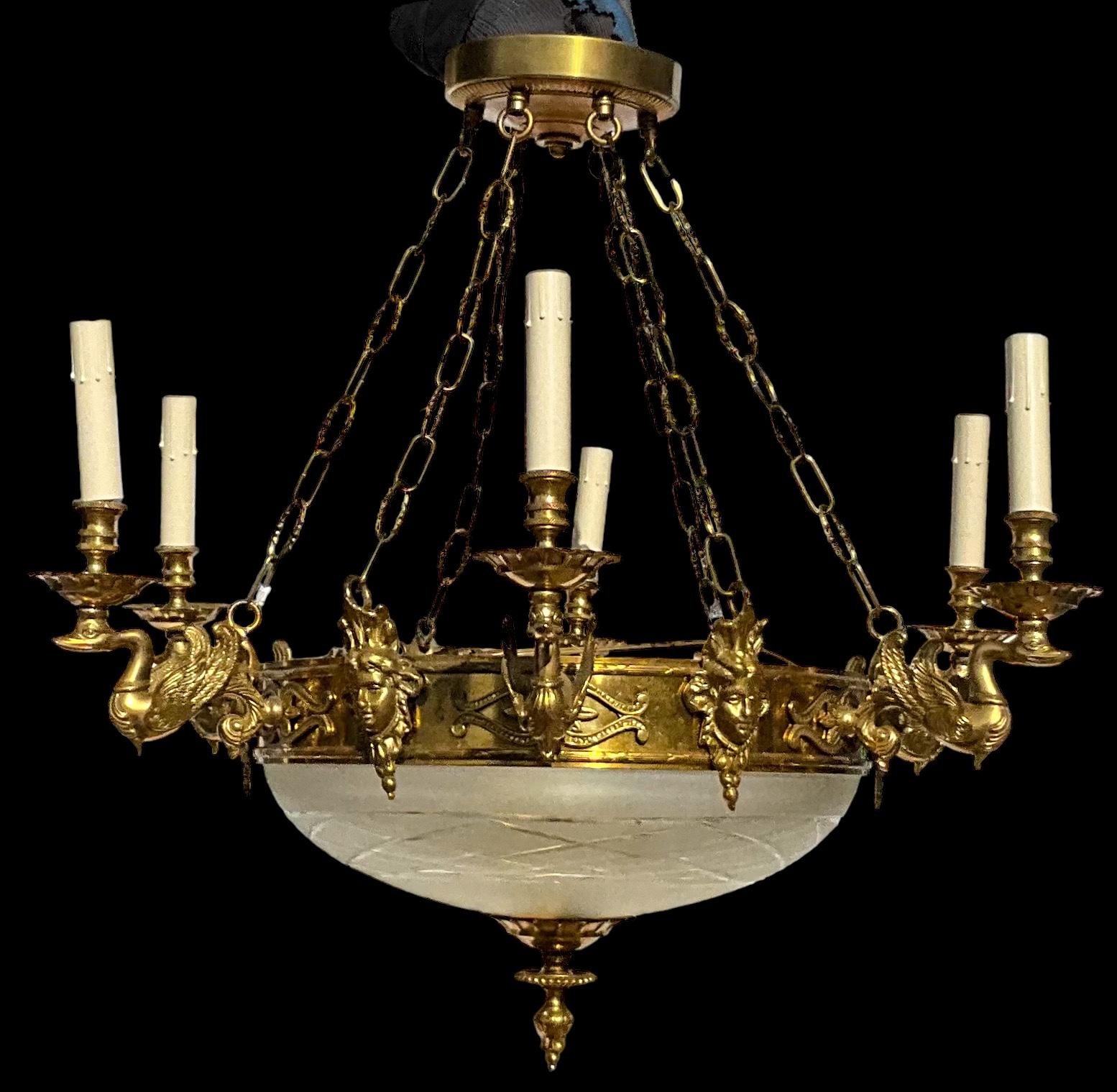 This is a French Empire style heavy brass chandelier. It is an Italian mid-century piece. The wiring has been completely re-done by a professional. There are six arms that are supported by swans. The bottom is a large etched glass globe. The cap is