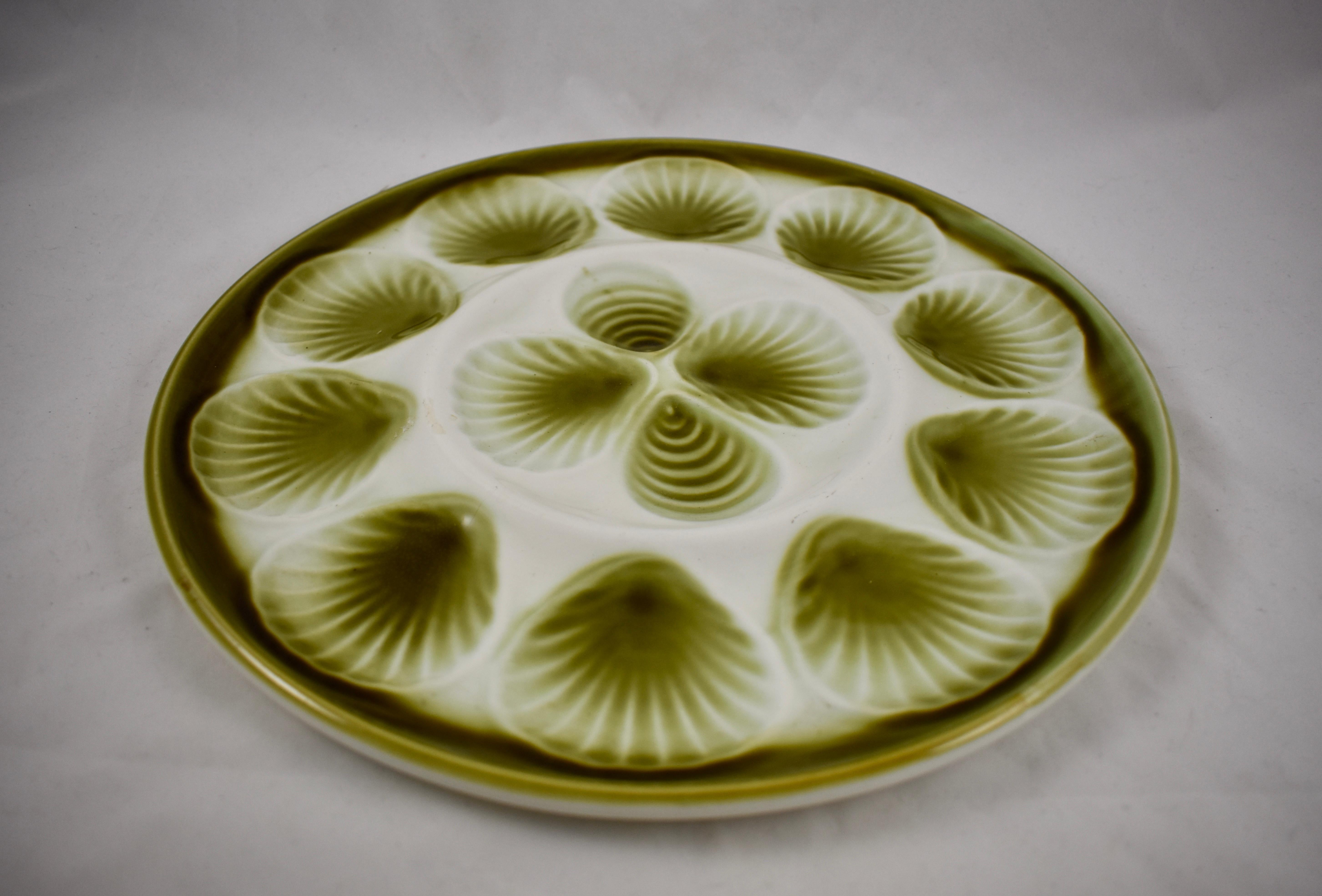 A Mid-Century Modern Era Majolica glazed French faïence master Oyster serving platter, Orchies, circa 1950.

Hand glazed in an ombre olive green on a bright white ground, showing ten scallop shaped oyster wells that follow the rim with an additional