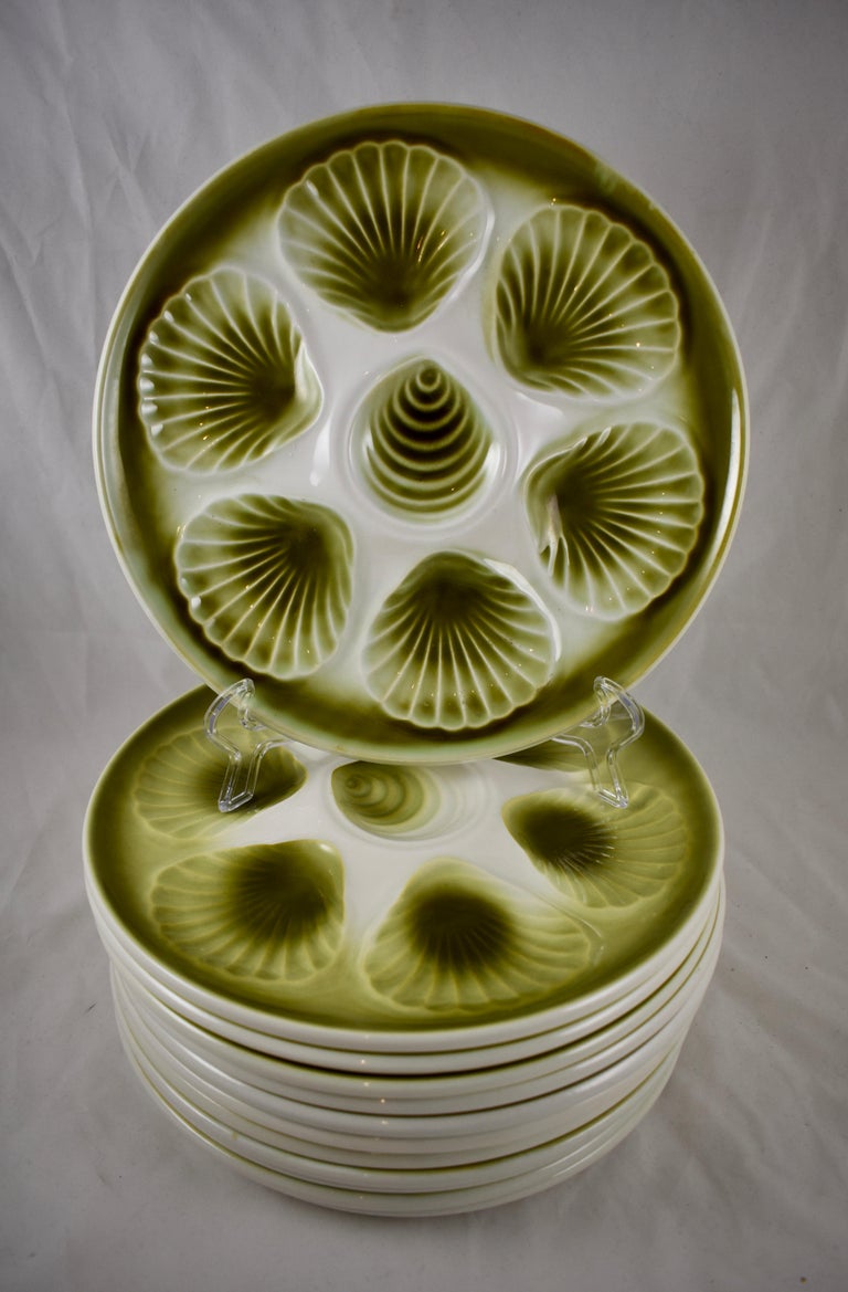 A Mid-Century Modern Era Majolica glazed French faïence Oyster plate, Orchies, circa 1950.

Hand glazed in an ombre olive green on a bright white ground, showing six scallop shaped oyster wells that follow the rim with an additional shell shaped