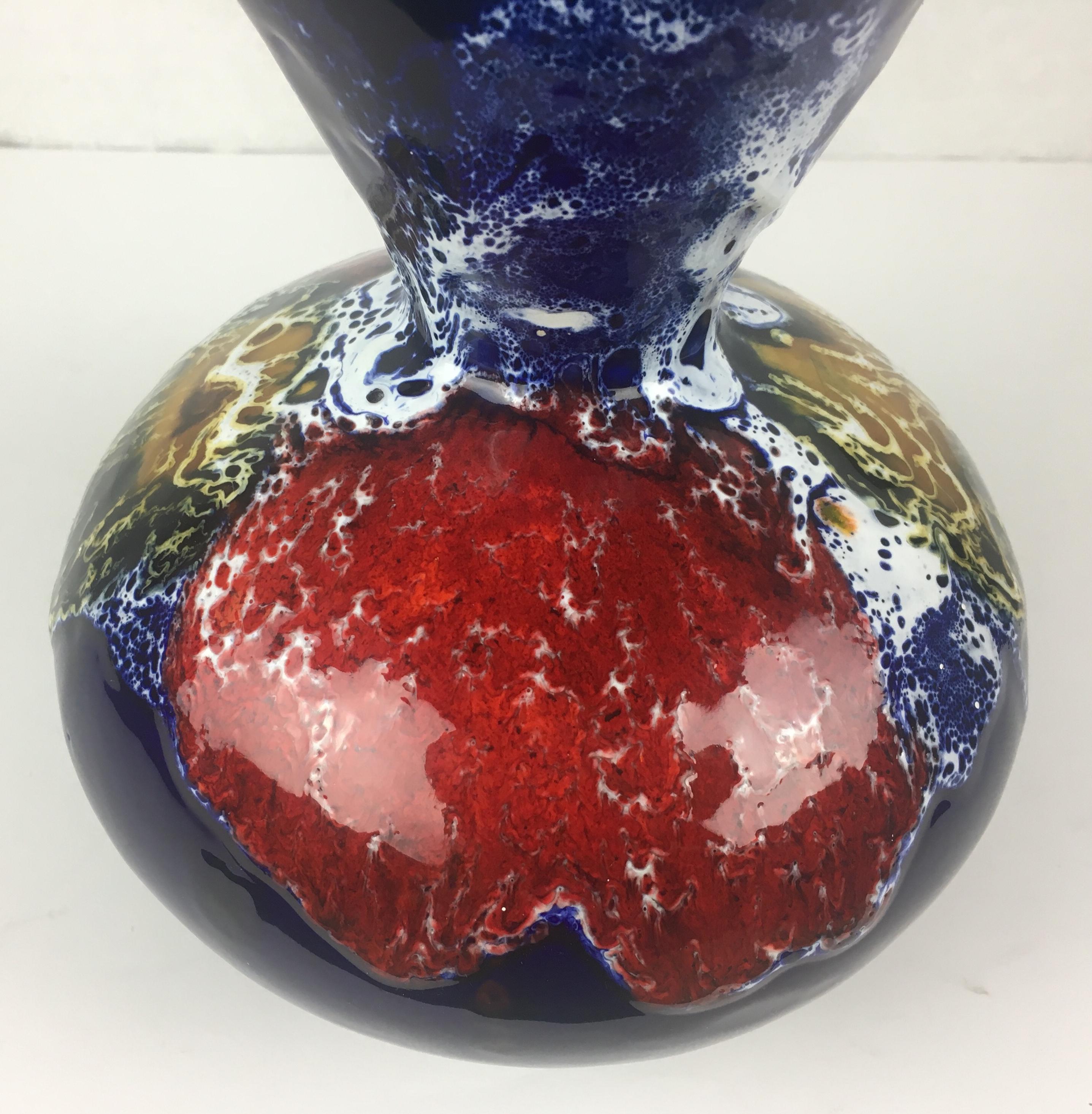 Diese schillernde, mehrfarbig glasierte Keramikvase aus fetter Lava wurde in den 1950er oder 1960er Jahren in Vallauris, Frankreich, handgefertigt. Die Grundfarben Blau, Rot und Weiß sind atemberaubend.

Er kann jedes Regal, jeden Tisch, jede