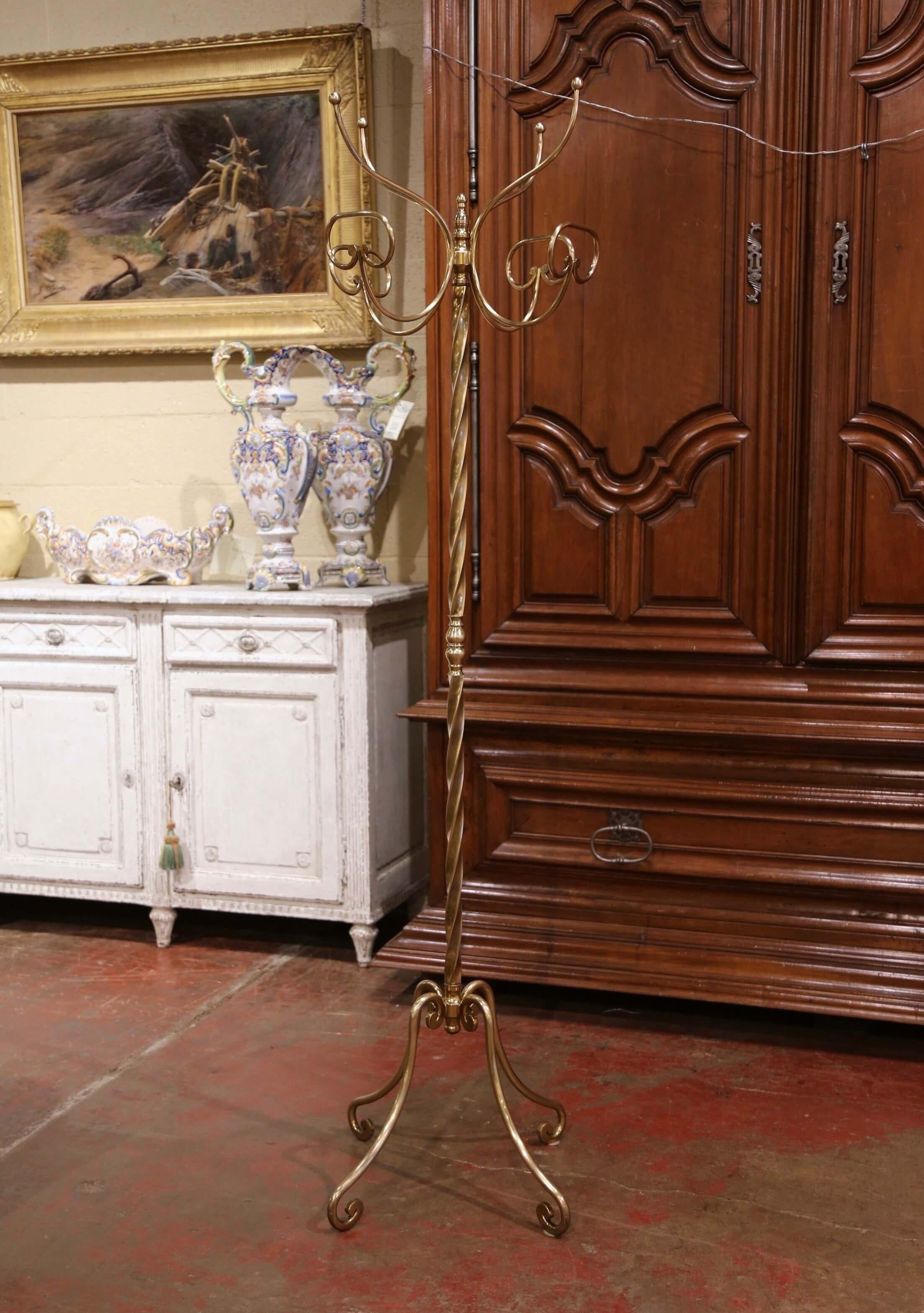 Crafted in France circa 1950, the tall antique rack stands on four scrolled legs over a twisted stem embellished with turned motif in the middle. The swivel top features four double arms ending in hat and coat hooks. The elegant Art Deco hat rack is