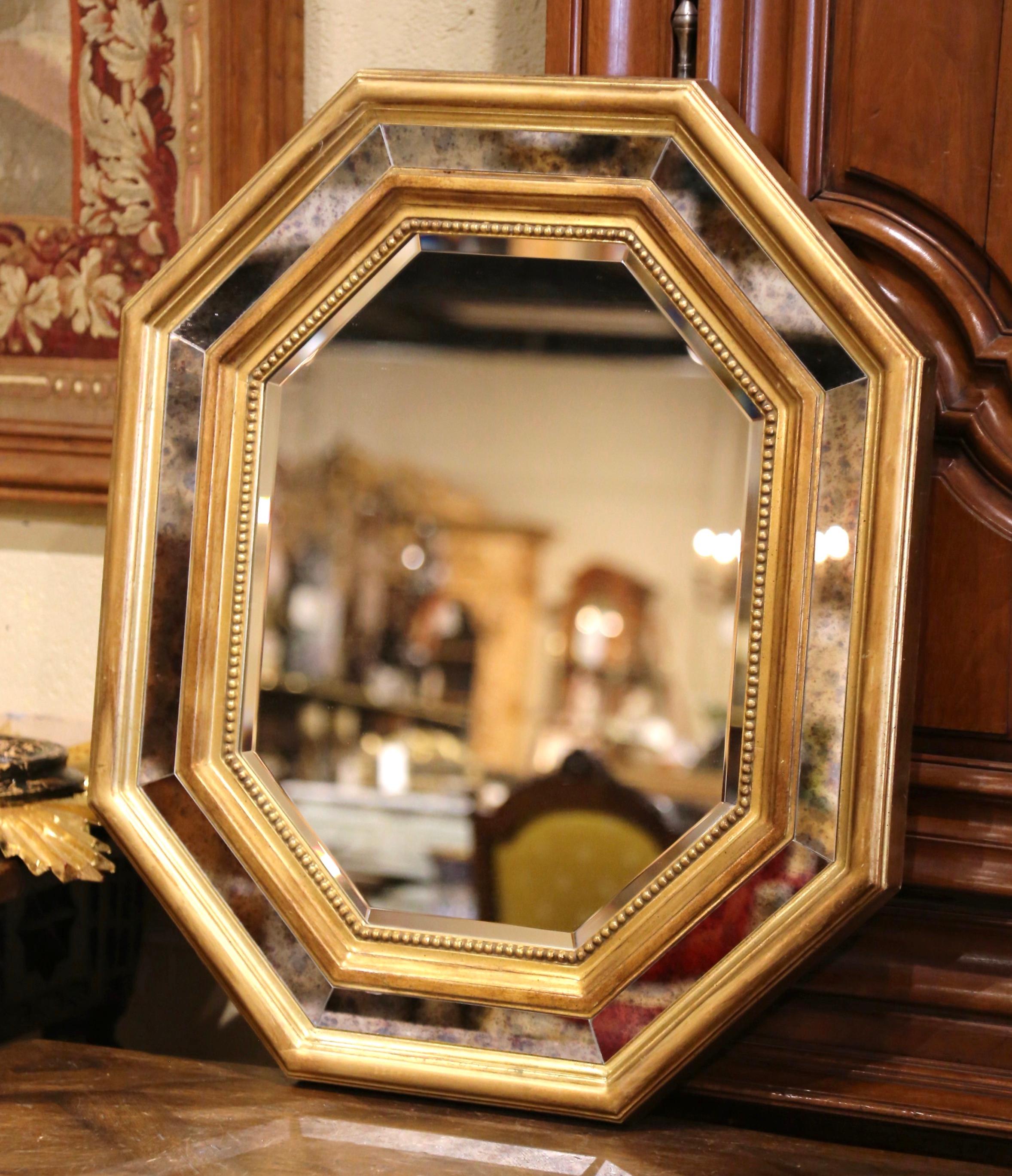 Decorate a powder room or entry with this elegant wall mirror. Created in France, circa 1970, and octagonal in shape, the mirror features eight smoked glass panels separated with gilt wood partitions with a center beveled glass decorated with bead