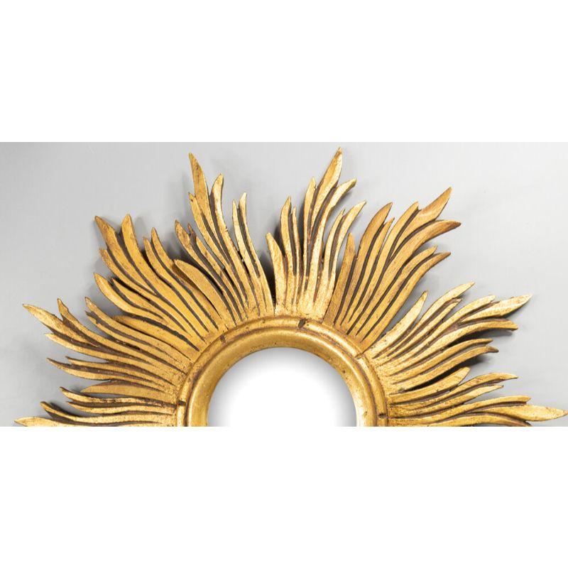 A beautifully carved vintage French giltwood sunburst mirror. This gorgeous mirror has a lovely gilt patina with undulating finely carved rays. These sunburst mirrors are beautiful displayed in groupings of various sizes and styles.

