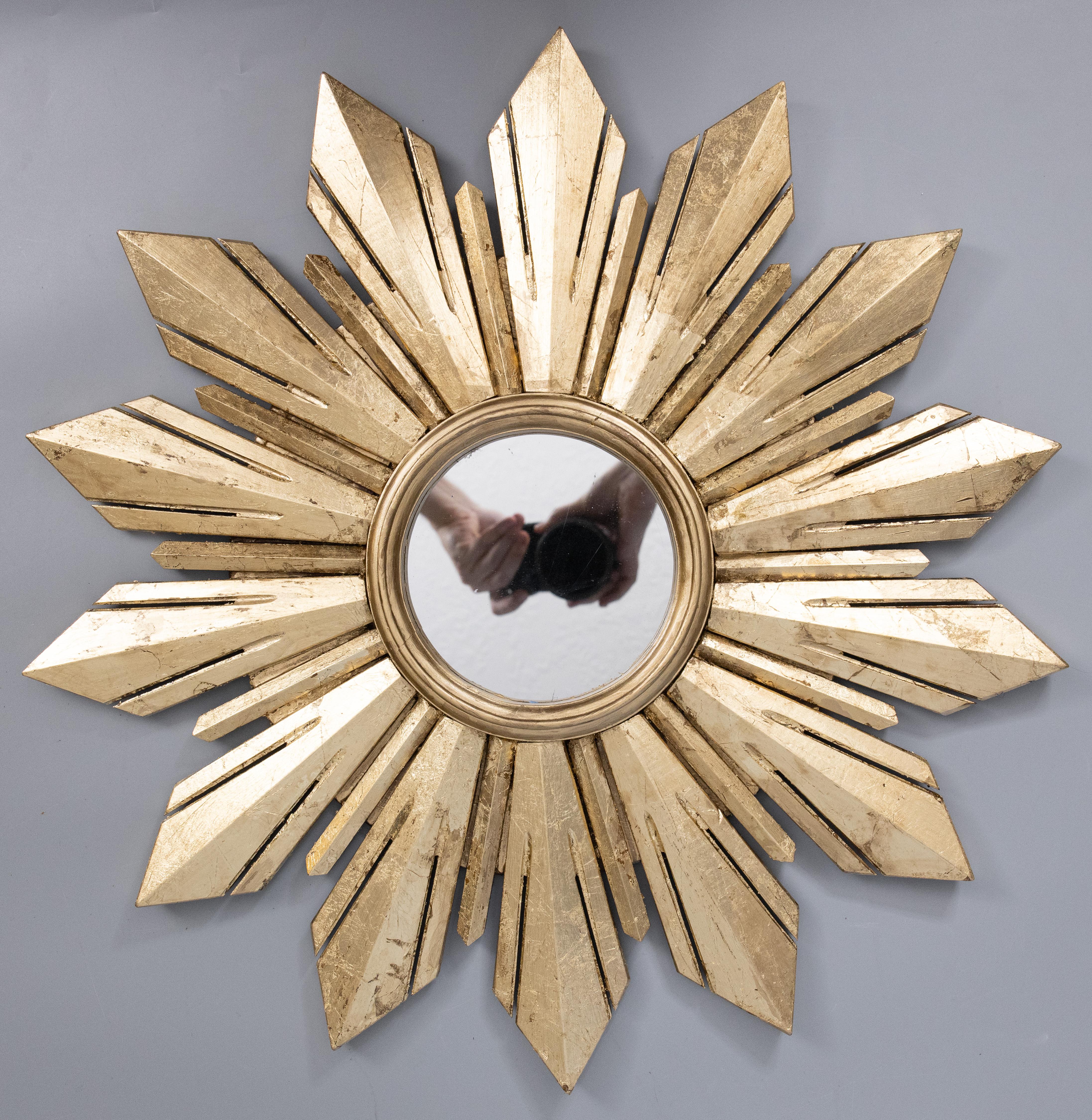 A stunning mid 20th-century French gold leaf gilded wood sunburst / starburst mirror. This fabulous mirror has a gorgeous gilt patina and stylish modern design. These sunburst mirrors are beautiful displayed in groupings of various sizes and