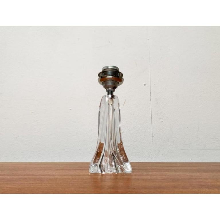 Lámpara de cristal de mediados de siglo del fabricante francés Daum.

Llaman la atención los pies de cristal con forma orgánica de este fabricante. La base es de grueso cristal transparente y parece un pedestal escultórico. La transparencia en