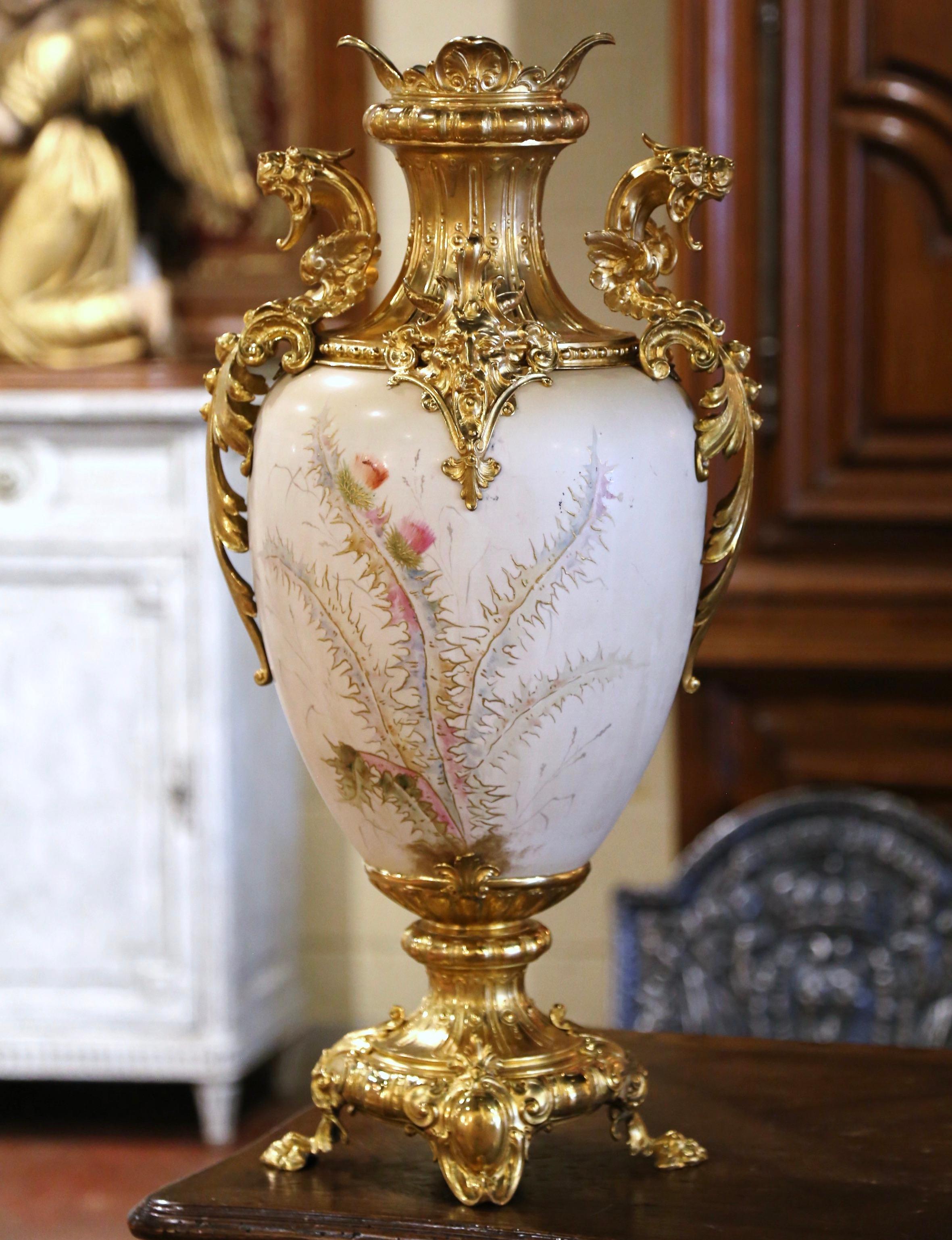 Decorate a console, commode, or table with this elegant and colorful decorative urn. Crafted in France circa 1960 and built of gold platted brass and porcelain, the tall vase features mythical creature mounts, including two winged lion handles and