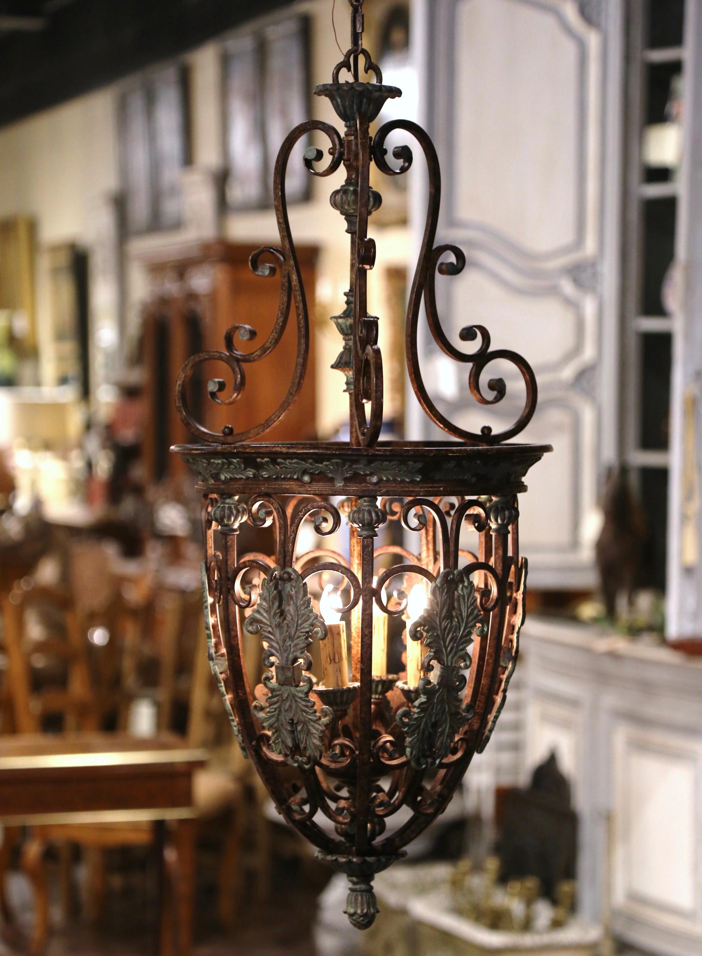 Crafted in France circa 1970, and round in shape with olive form, the two-tone lantern features a scrolled top, and is decorated with a pierced ornate body embellished with acanthus leaf and floral motifs, and dressed with a cone finial at the