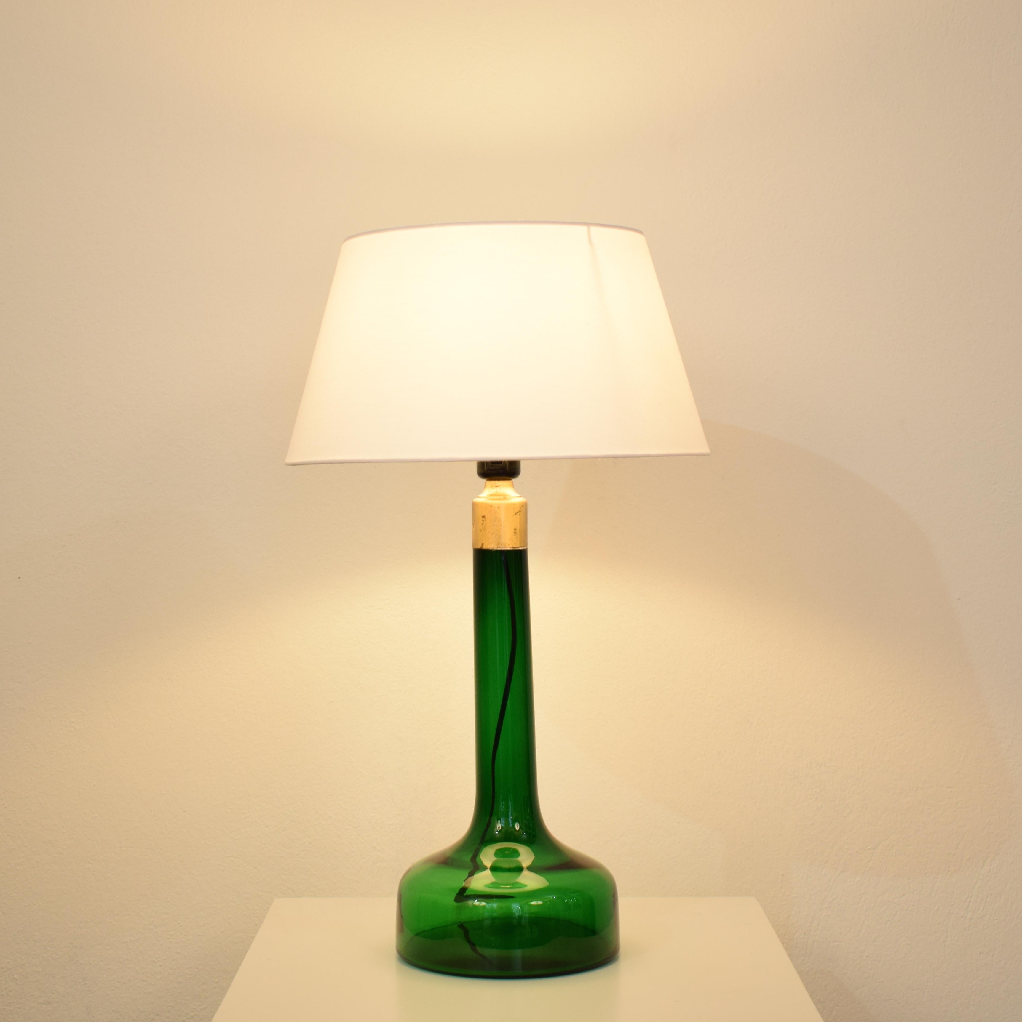 This elegant midcentury French table lamp was produced, circa 1970.
The lamp is made out of a deep green glass which gives a beautiful light.
The shade is replaced and in a white fabric.

A unique piece which is a great eyecatcher for your antique,
