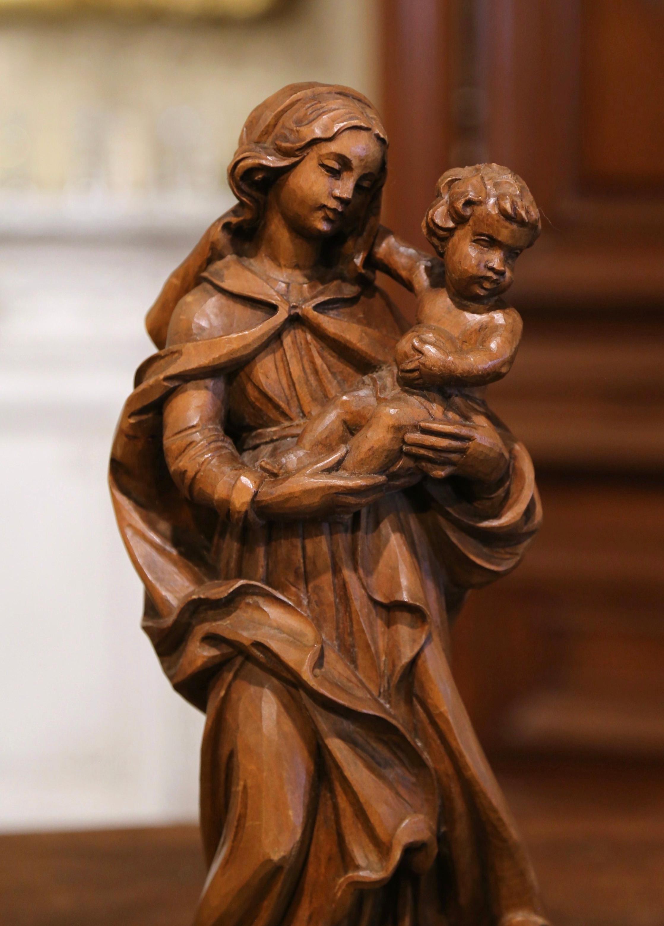 This elegant antique statue of the Mother and Child, was carved in Southern France, circa 1960. The large alluring sculpture in high relief, features Madonna holding her Son, our Lord Jesus Christ. Jesus is holding what looks to be a bowl in his