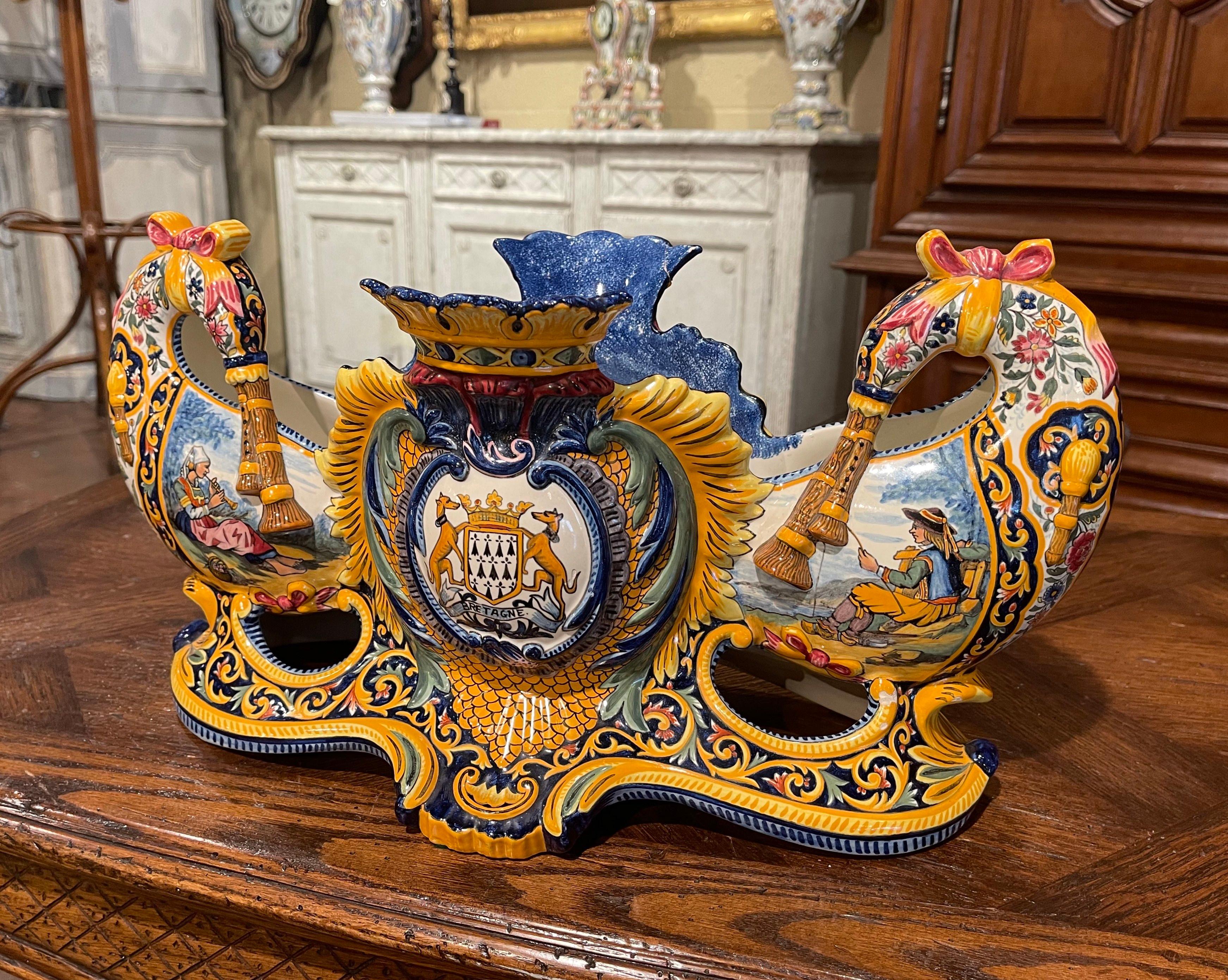 This elegant and colorful antique cachepot was sculpted in Brittany, France, circa 1960. The uniquely oblong shaped planter with double- bagpipe handles, and is decorated with hand painted center medallions set inside a crown and leaf motif frame in