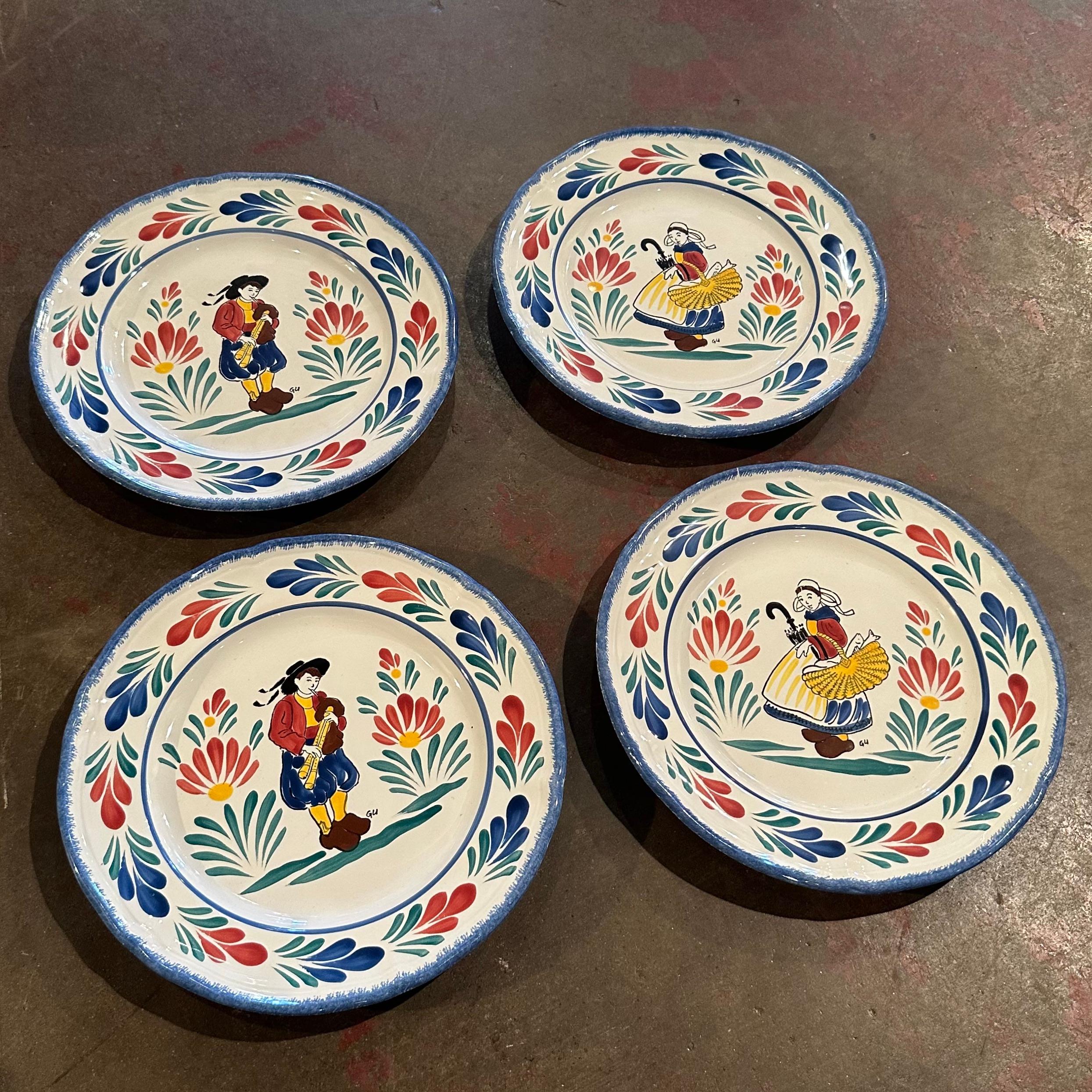 Decorate a shelf with these 2 pair of vintage decorative plates from Brittany, France. Crafted circa 1980, each faience plate is hand painted and features Breton people in traditional costumes in the style of Quimper pottery. The plates are signed