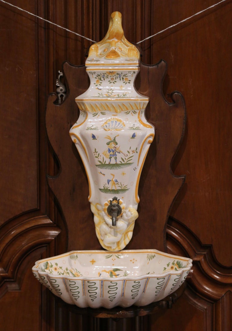 Decorate a wall with this elegant ceramic fountain on board from the south of France. Crafted in Moustiers circa 1960, the decorative three-piece set is complete with basin, reservoir with metal spout, and lid; the lavabo is attached to a carved