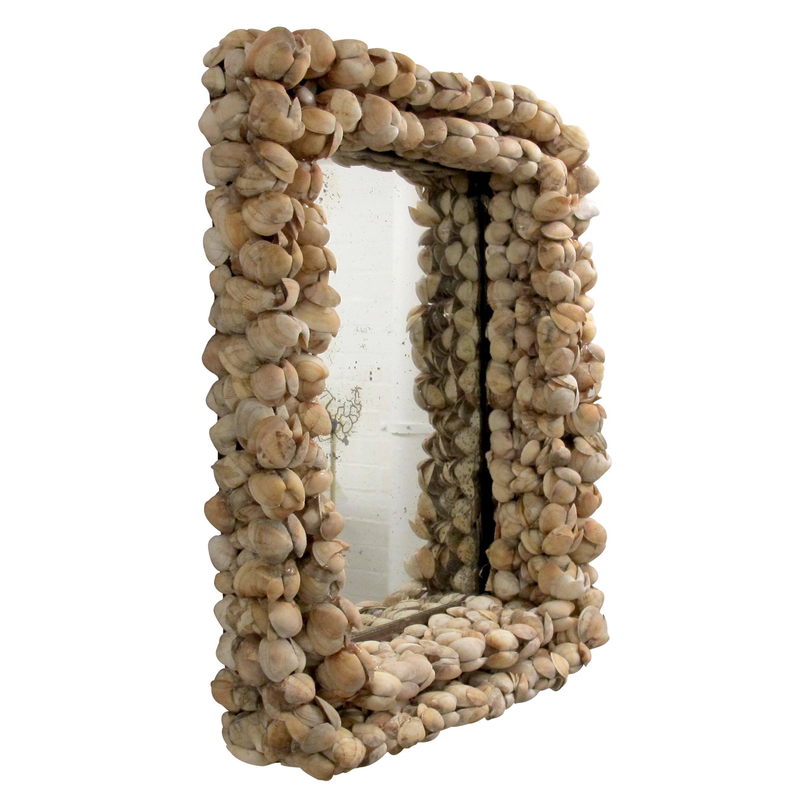 This stunning mid-century French mirror is a testament to artisanal craftsmanship, featuring a meticulously handcrafted frame adorned with natural clam seashells. The three-dimensional layered design creates a rich texture, giving the piece a