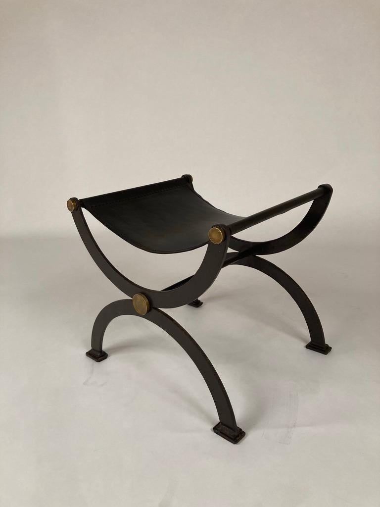 A modern version of the classic X stool in wrought iron with a wonderful dark chocolate lacquered finish and round bronze decorative bosses. Leather sling seat. The clean lines of this bench are the definition of elegance. French, 1960's. 
21.25