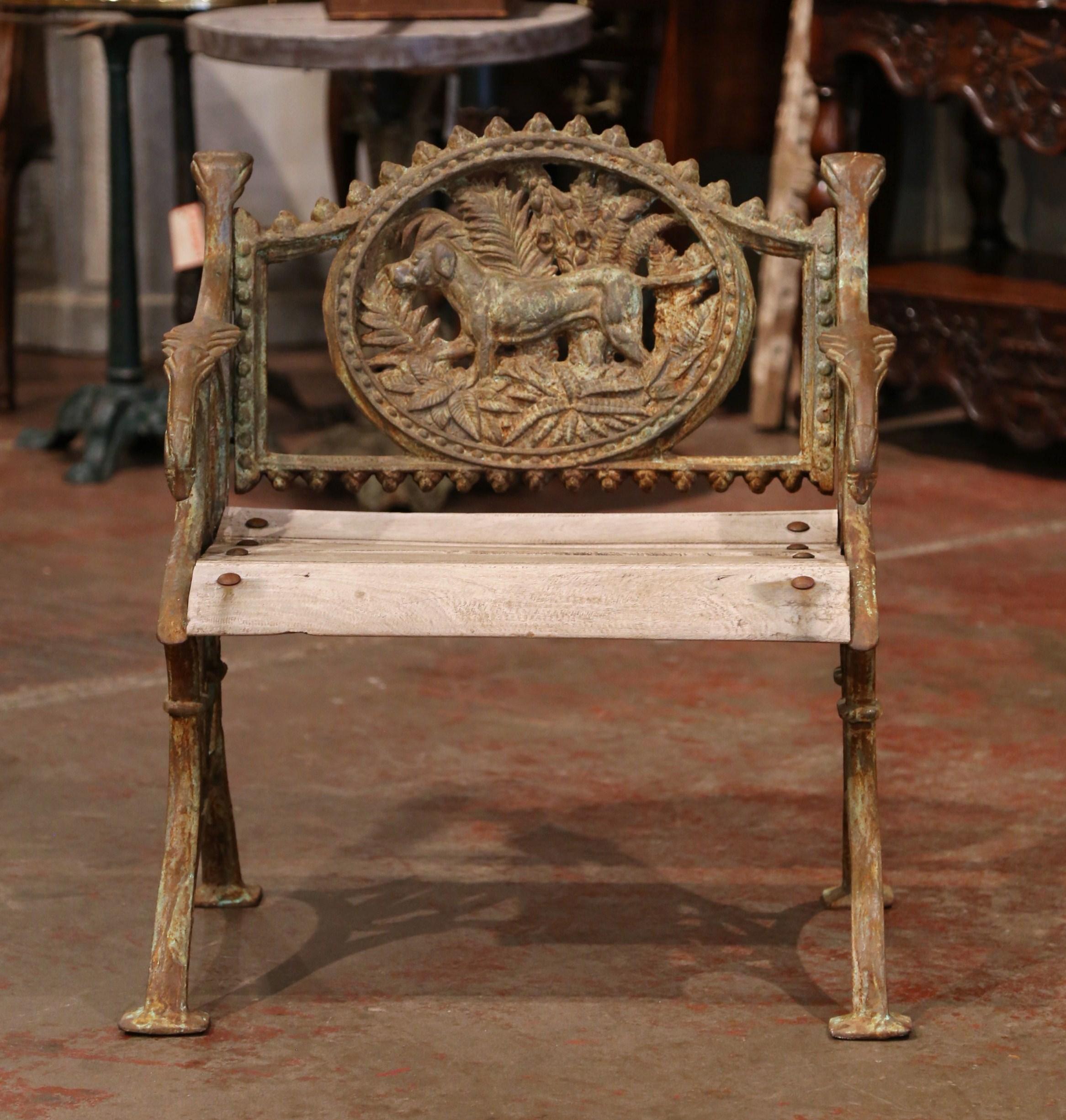 Decorate a patio with this antique outdoor chair. Crafted in France circa 1960, the armchair is made of iron and teak wood. It sits on curved feet decorated with bird motifs, and features an arched back decorated with a carved dog sculpture. The
