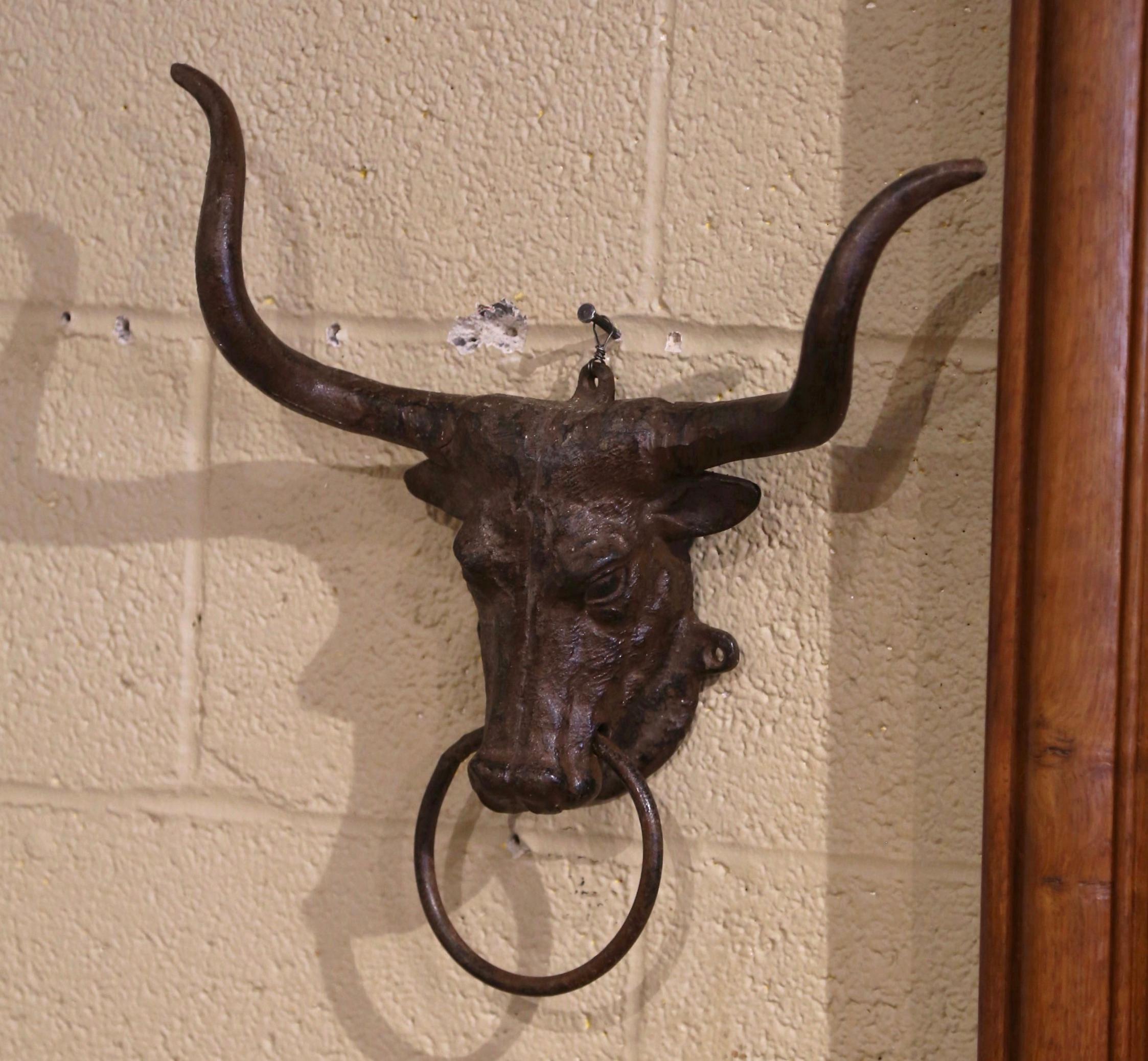 This beautiful antique cow head sculpture was crafted in France circa 1960. The hand crafted work of art, features a realistic bull head with two large horns and dressed with a metal ring through the nostrils. The wall decor is in excellent