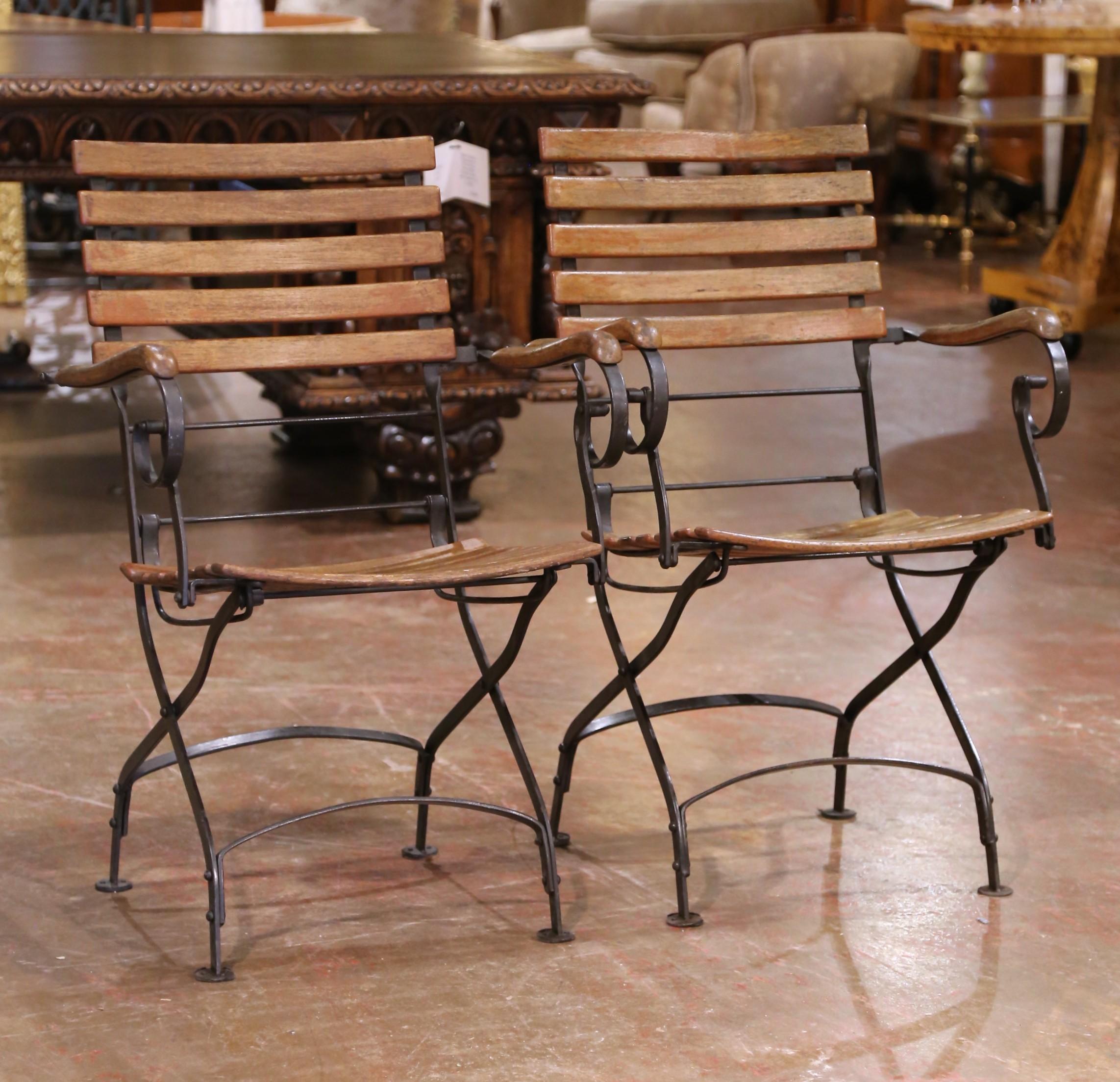 Fabriquée en France vers 1970, cette paire de chaises de jardin pliantes du milieu du siècle allie un design épuré et fonctionnel à un charme durable. Chaque chaise est dotée d'un solide cadre en fer forgé à la main, avec des supports d'accoudoirs