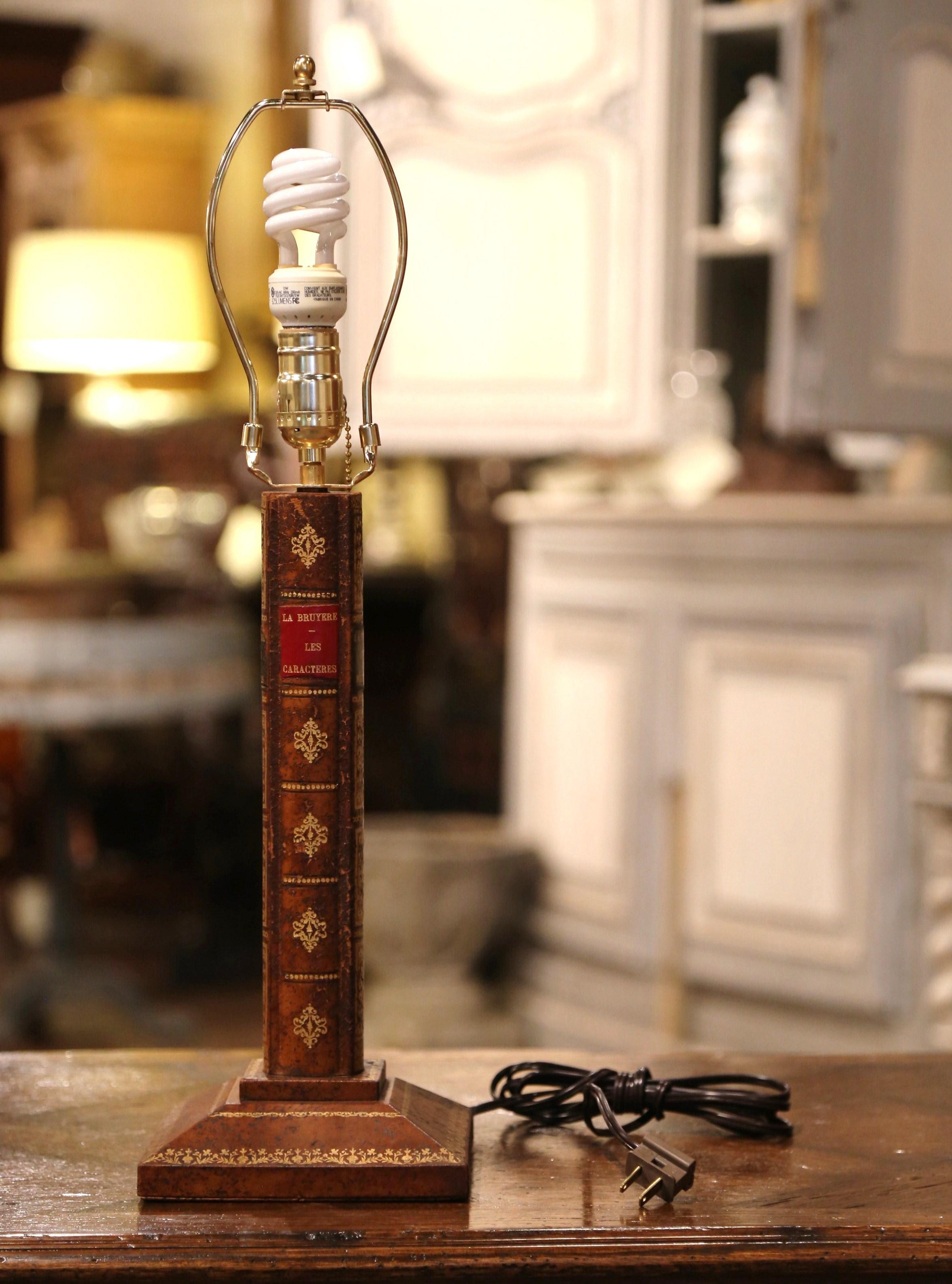 Decorate a desk or a writing table with this elegant vintage lamp. Crafted in France circa 1970, the fixture stands on a square base with felt and has new wiring; the stem is made of four leather spines and raised bands, and decorated with two 17th