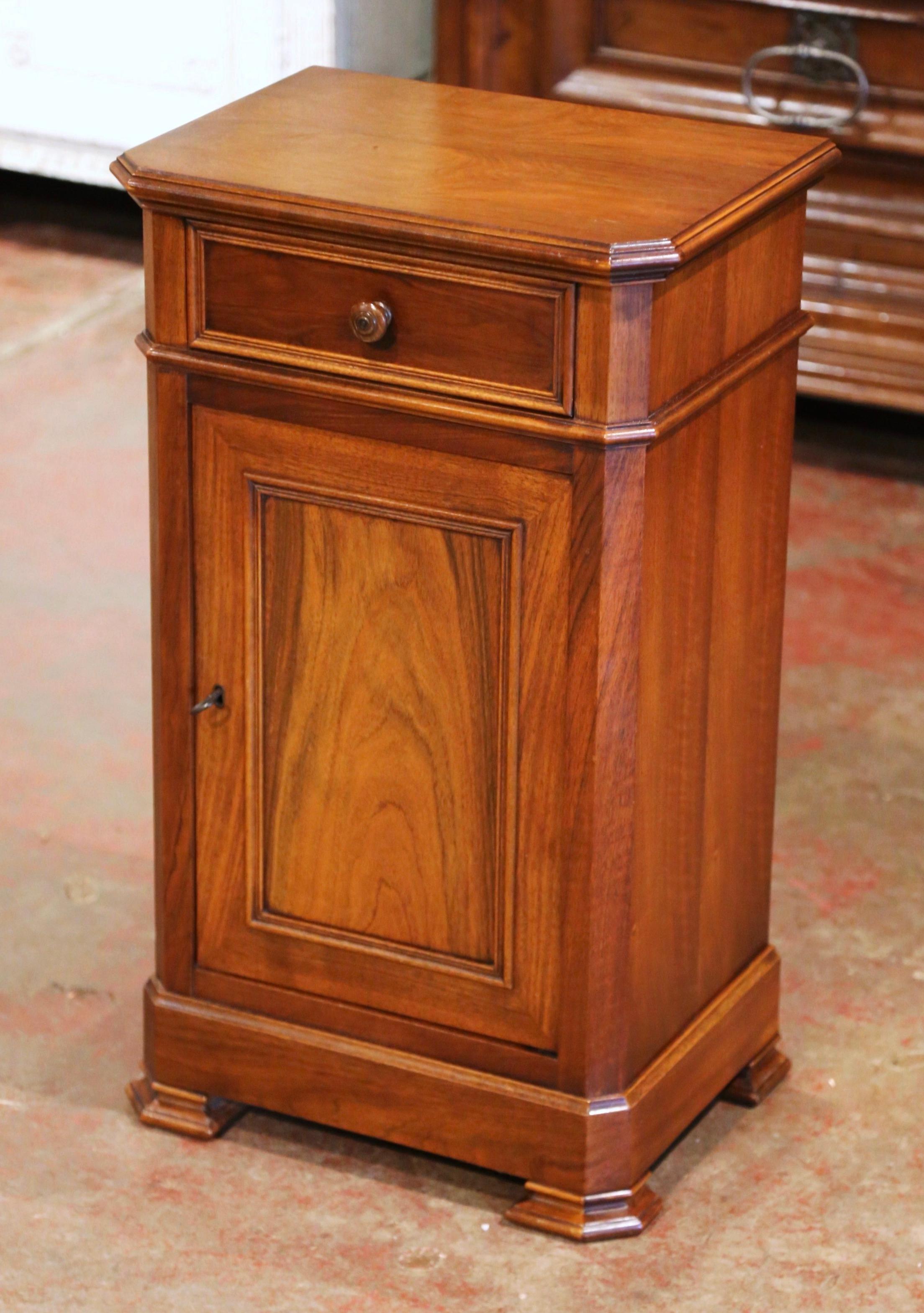 This elegant antique nightstand was crafted in France, circa 1970. The traditional fruit wood cabinet sits on bracket feet over a wide bottom plinth; it is fitted with a single drawer dressed with wooded knob, over a front door with raised panel,