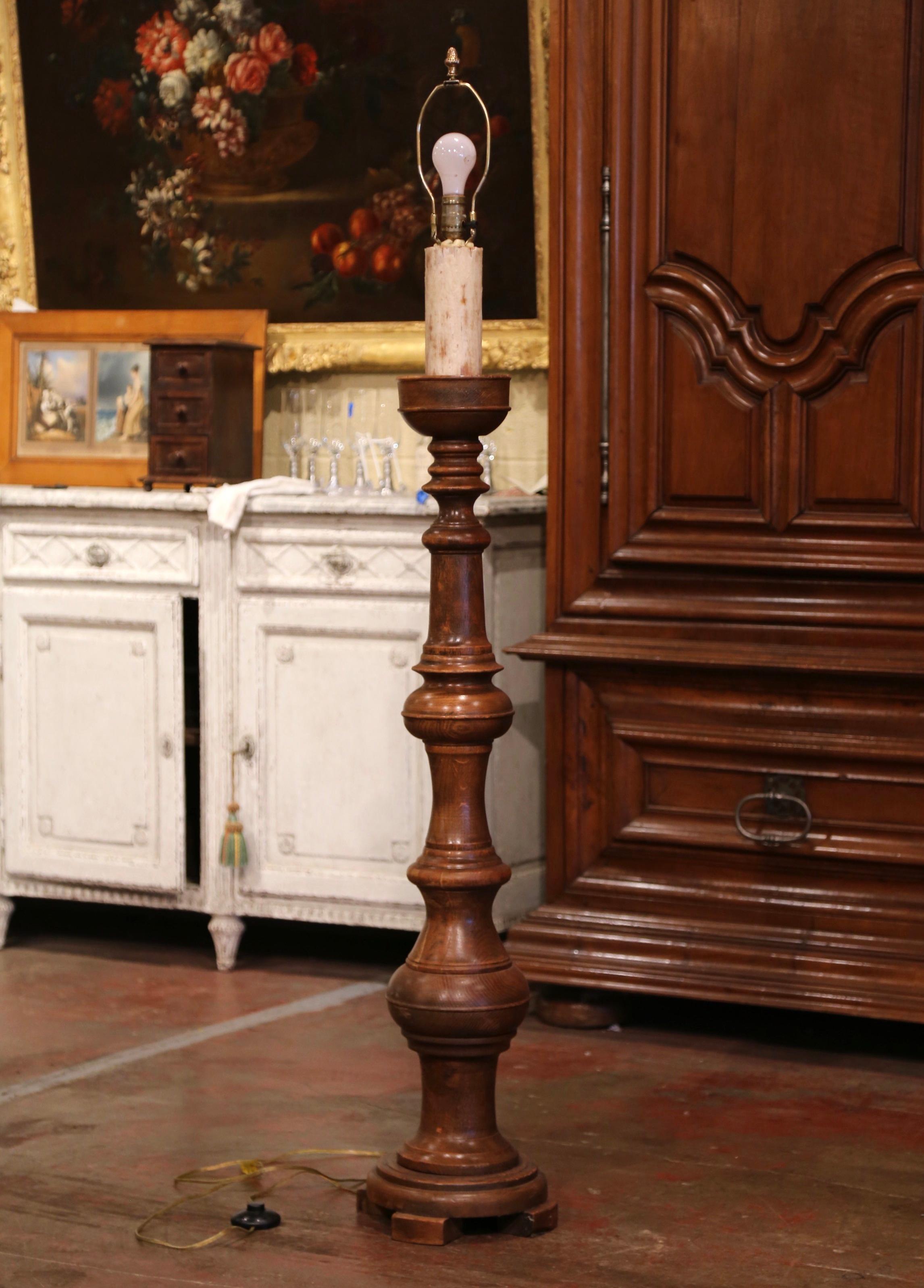 This elegant antique carved lamp was crafted in France, circa 1950. The fixture stands on a circular base with three small feet over a long turned stem. The lamp with a single center light is embellished with a large wax candle. The floor lamp is in