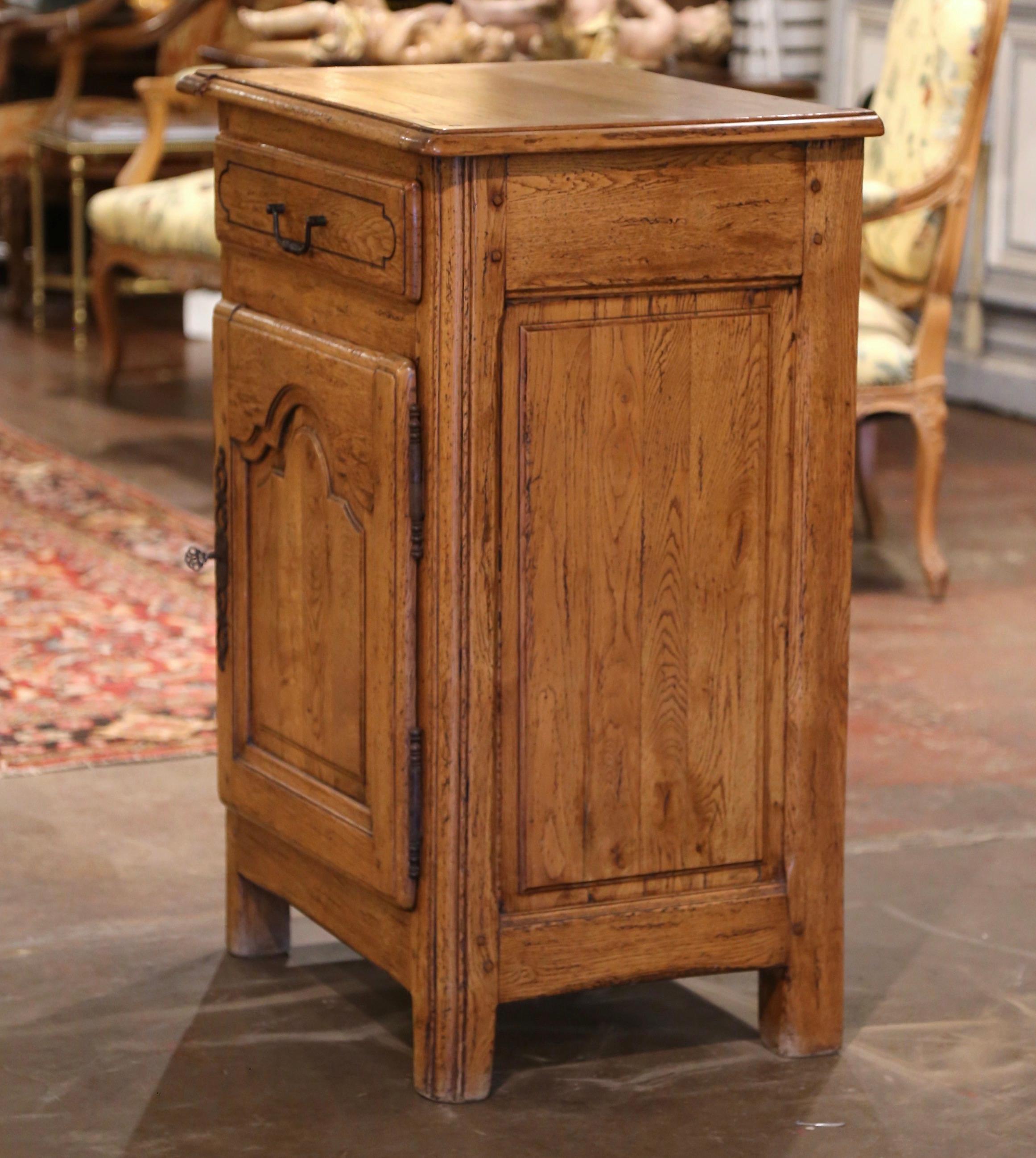 This elegant antique oak cabinet was crafted in Normandy, circa 1970. The provincial confiturier is fitted with a single drawer dressed with iron handle, over a center door decorated with carved raised and arched panel. The inside reveals a middle