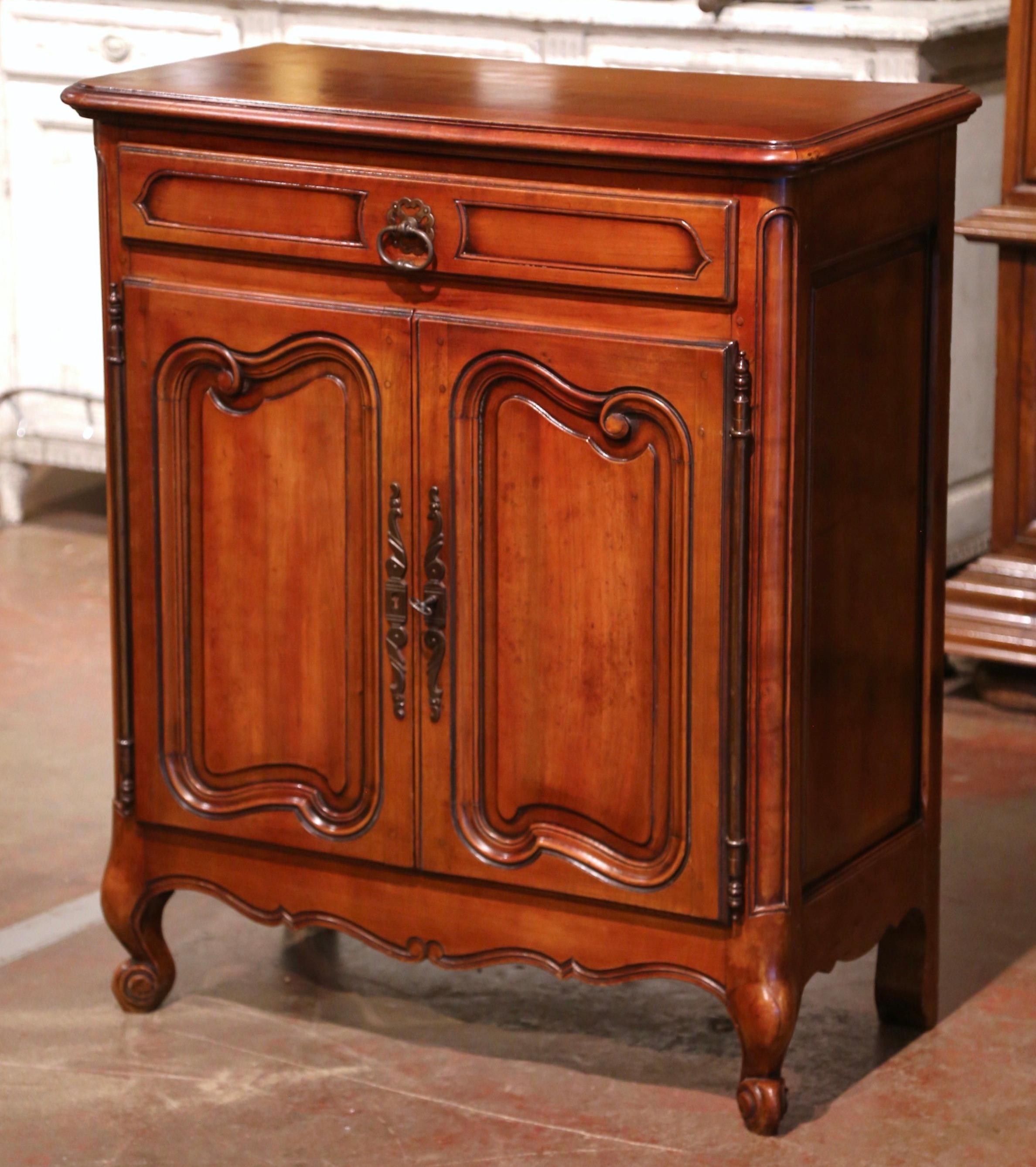 This antique fruit wood buffet was crafted in Southern France, circa 1960; the confiturier (French for jelly cabinet), sits on escargot feet over a scalloped apron; it features a large center drawer with recessed panel over two carved doors