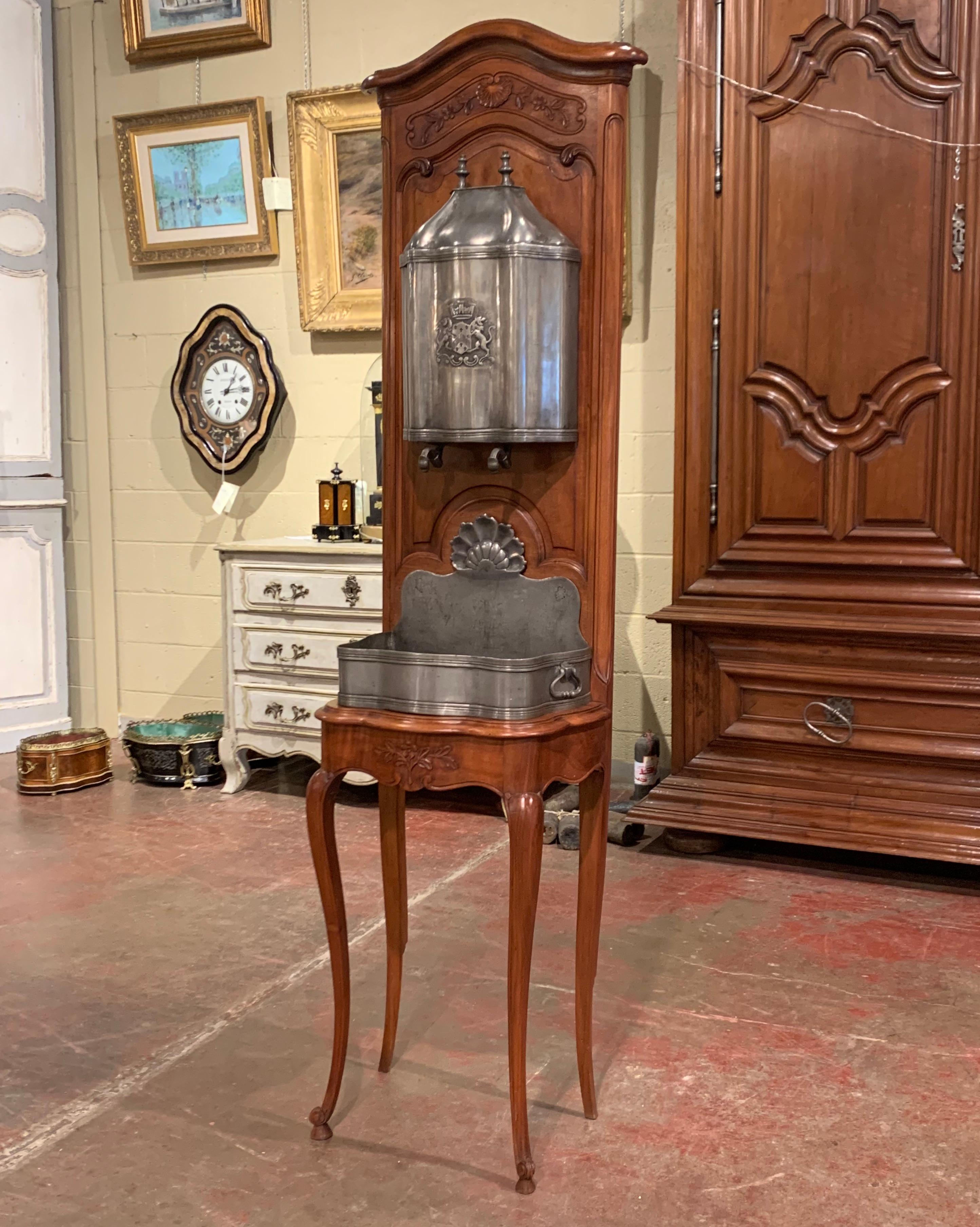 This elegant, antique fountain was crafted in Provence, France, circa 1950. The cabinet stands on cabriole legs over a scalloped apron, and the arched bonnet top features a carved shell motif with foliage. Made of pewter, the two-piece water