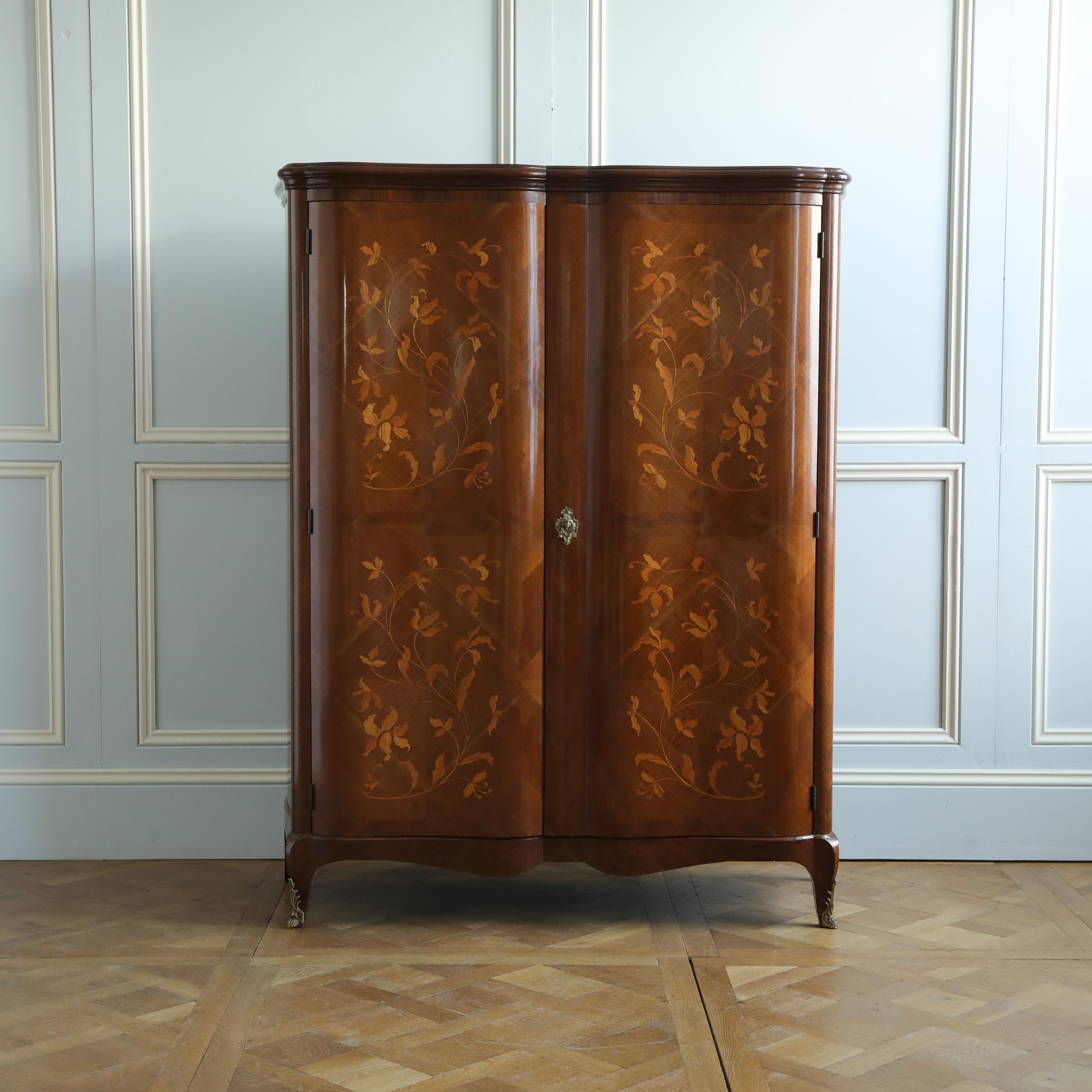 A pretty French, circa 1940's, serpentine style, two-door armoire with book-matched kingwood veneer work, featuring a striking design of inlaid floral marquetry on the doors and sides. This armoire has the benefit of being a neat size and height
