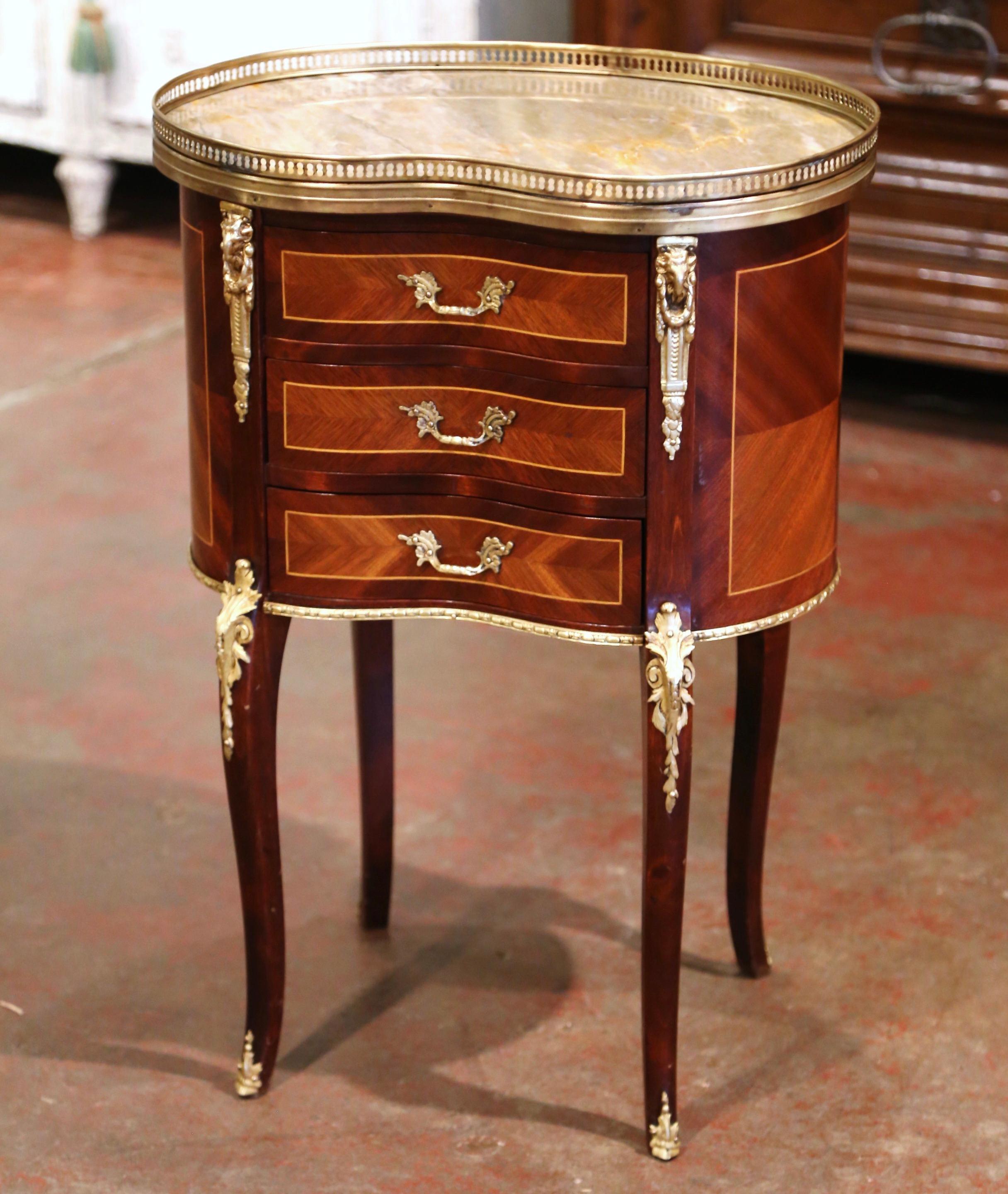 This elegant, kidney-shaped fruitwood antique chest was crafted in France circa 1950. The petite commode sits on cabriole legs decorated with acanthus leaf mounts at the shoulder, and ending with brass sabot feet; it features three drawers across