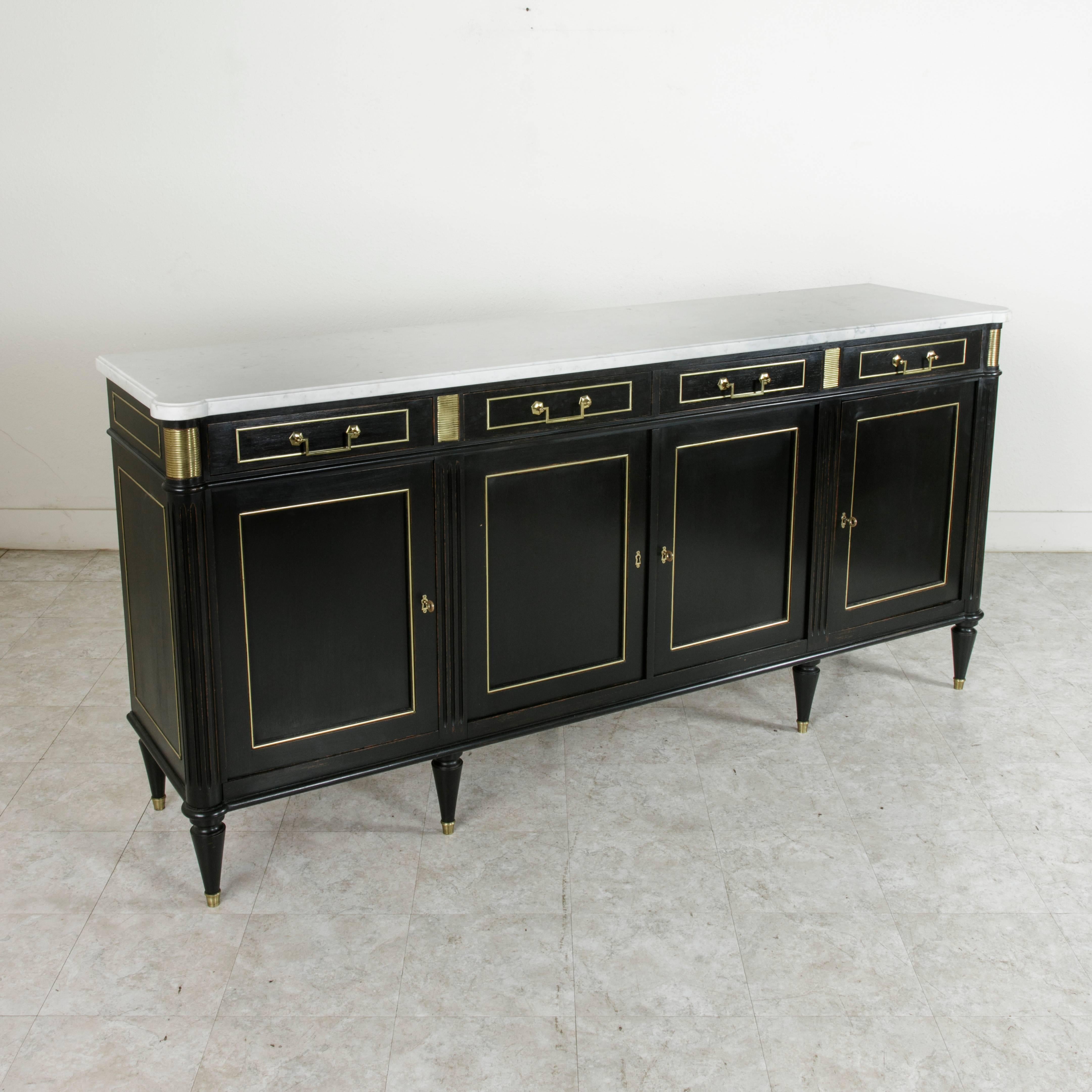 Louis XVI meets midcentury in this striking painted mahogany enfilade or buffet found in Normandy, France. Stunning bronze banding outlines each door, drawer, and panel, while striated bronze plaques define the facade. Its original white marble top