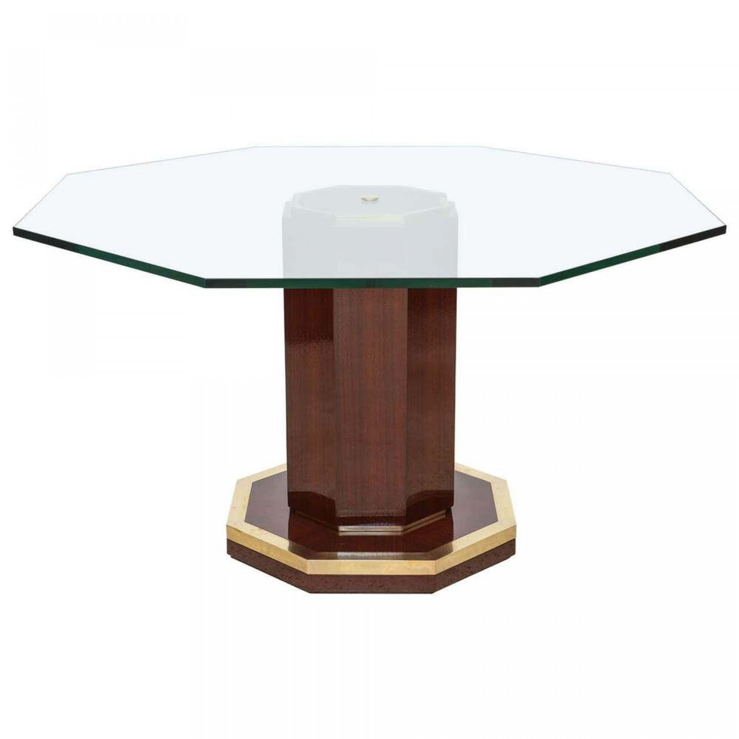 French Mid-Century Modern center table with an octagonal clear glass top resting on a pedestal base made of mahogany, ending in an octagonal brass-trimmed foot. (Attributed to JACQUES QUINET)