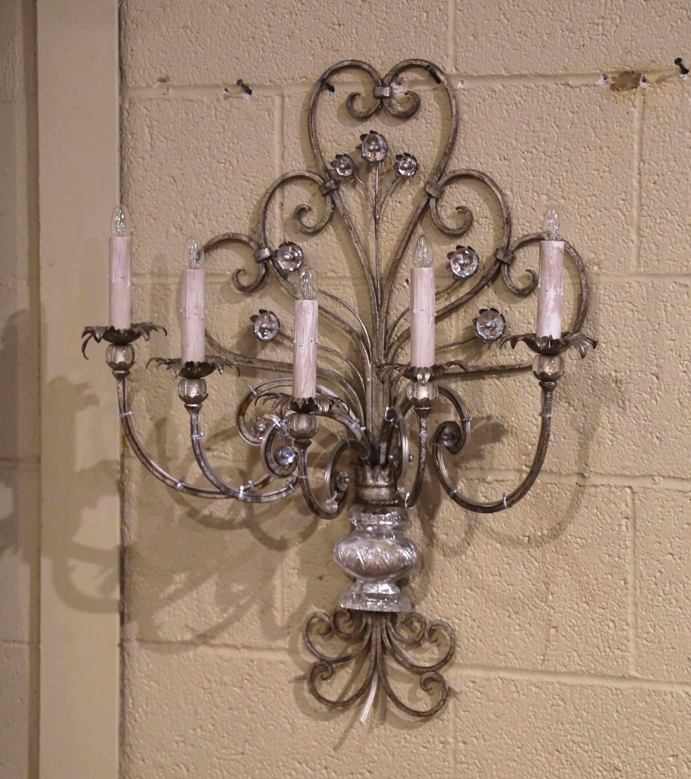 Questa elegante applique argentata, realizzata in Francia intorno al 1960, è attribuita alla Maison Baguès. Caratterizzato da cinque bracci in metallo graziosamente curvati, il design è impreziosito da un'urna di cristallo alla base e da delicati