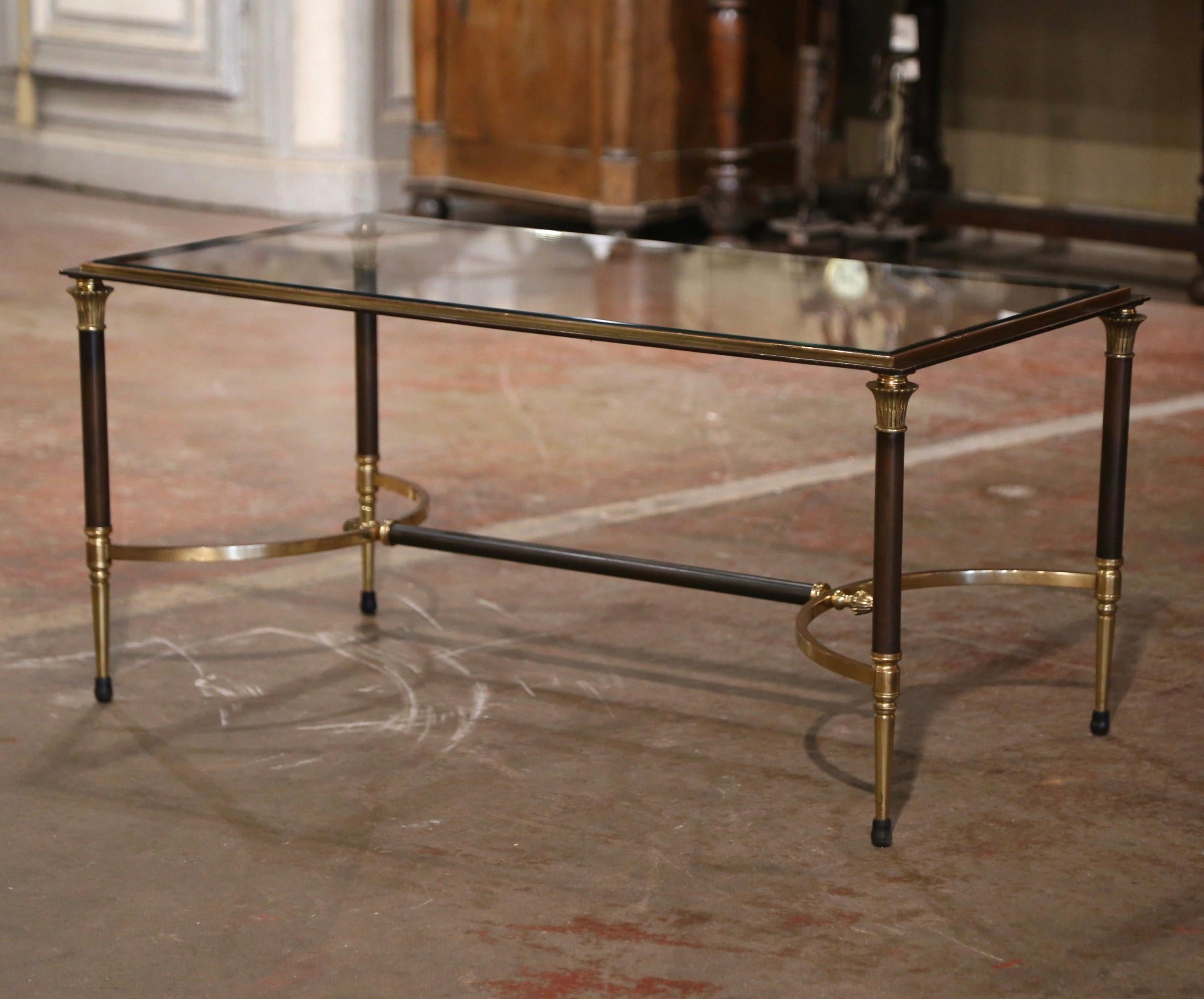 This elegant and slender cocktail table was crafted in France by Maison Charles circa 1960. The rectangular table stands on four fluted legs made of steel and brass embellished with an arched bottom stretcher dressed with end finials. The surface is