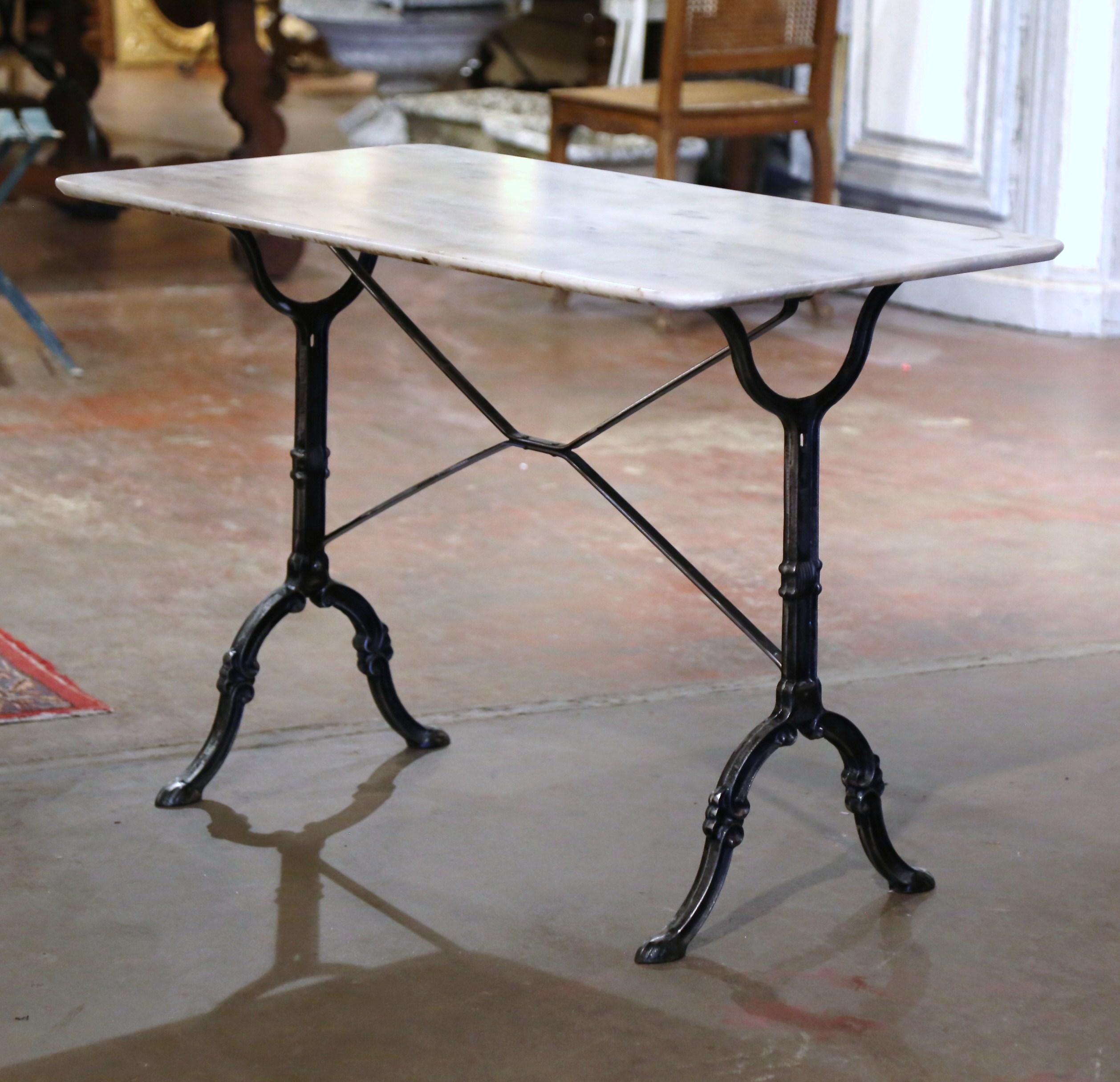Decorate a patio or covered porch with this elegant antique bistrot table. Crafted in France circa 1950, the cast iron table sits on a trestle base with elegant scroll legs ending with hoof feet, and joined together with a double decorative crossed