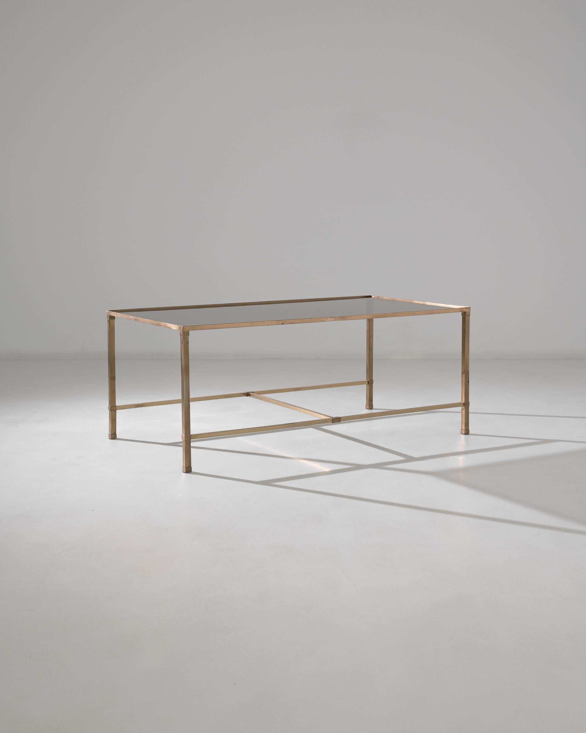 A minimalist metal coffee table with a glass top from 20th century France. True to mid-century aesthetics, this sharply designed coffee table is constructed with a light but sturdy touch. Thin, elegant brass square tubes connect to form an elegantly