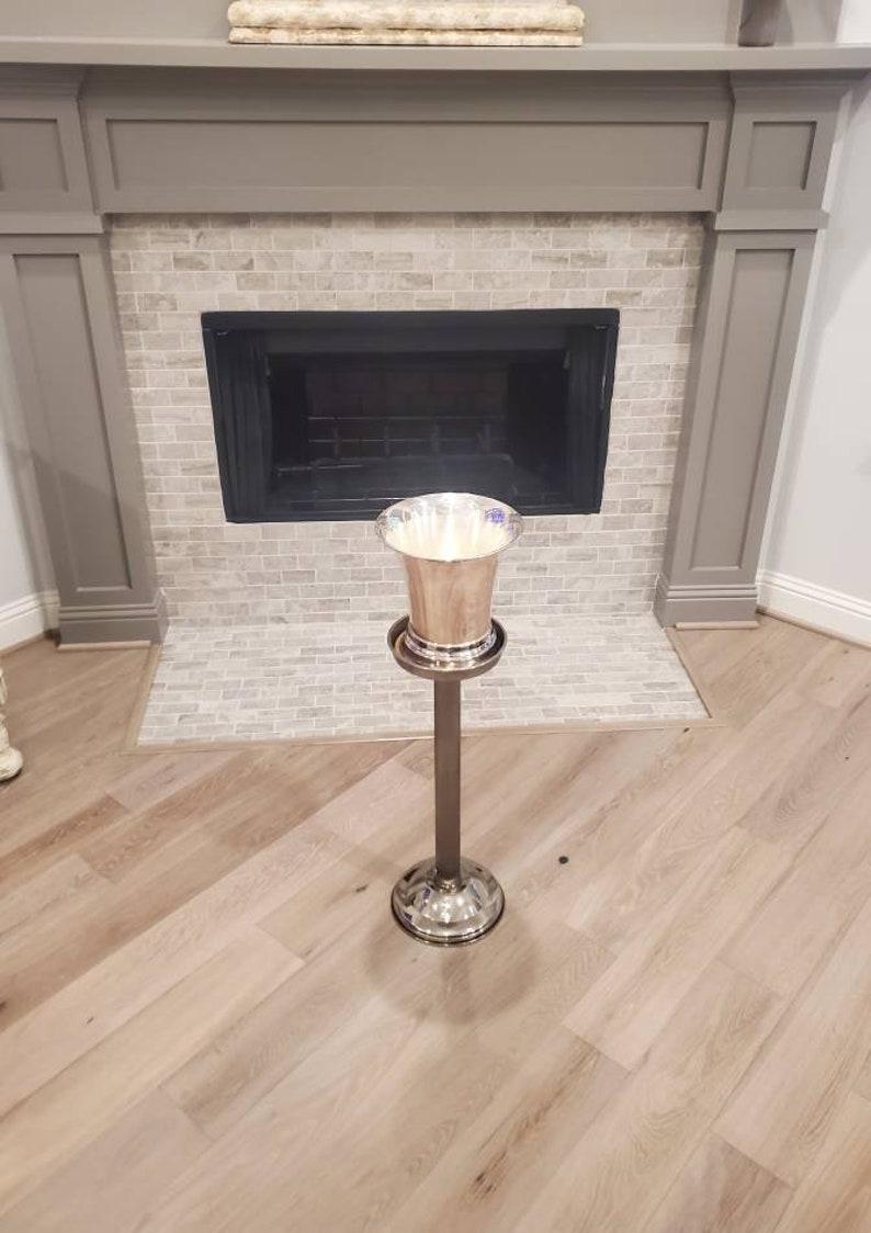 A vintage Mid-Century Modern silver plated champagne chiller ice bucket, atop a fluted column Stand with sturdy weighted circular base and cork padded top for additional stability. The Art Deco inspired French Modernist design is both luxurious and