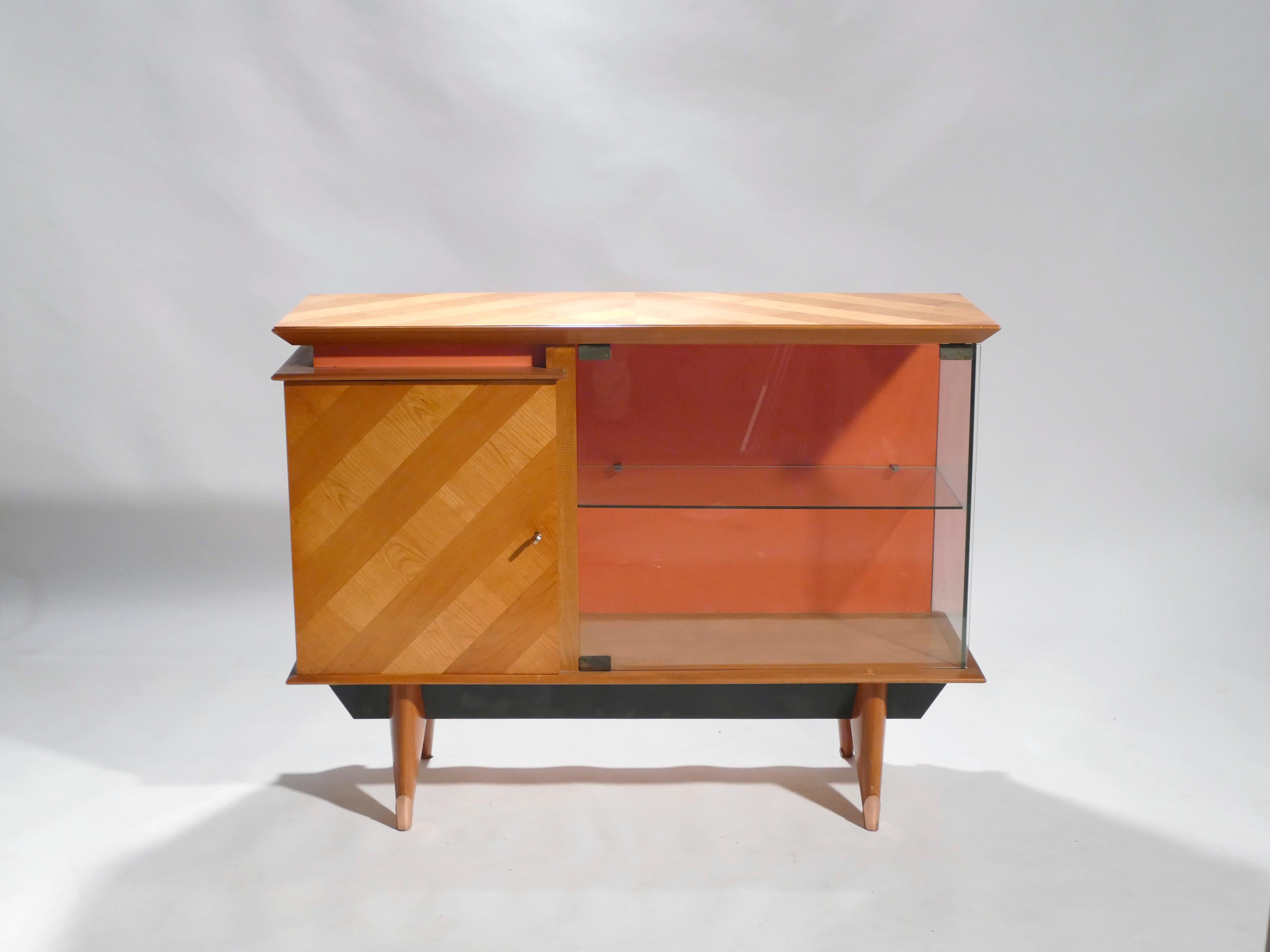 Le chêne brun clair chaud et le cuivre riche forment une belle palette de couleurs dans ce meuble vaisselier des années 1950. Sur le devant et le dessus du meuble, le chêne présente un motif rayé bois clair/bois foncé qui est amusant et tout à fait