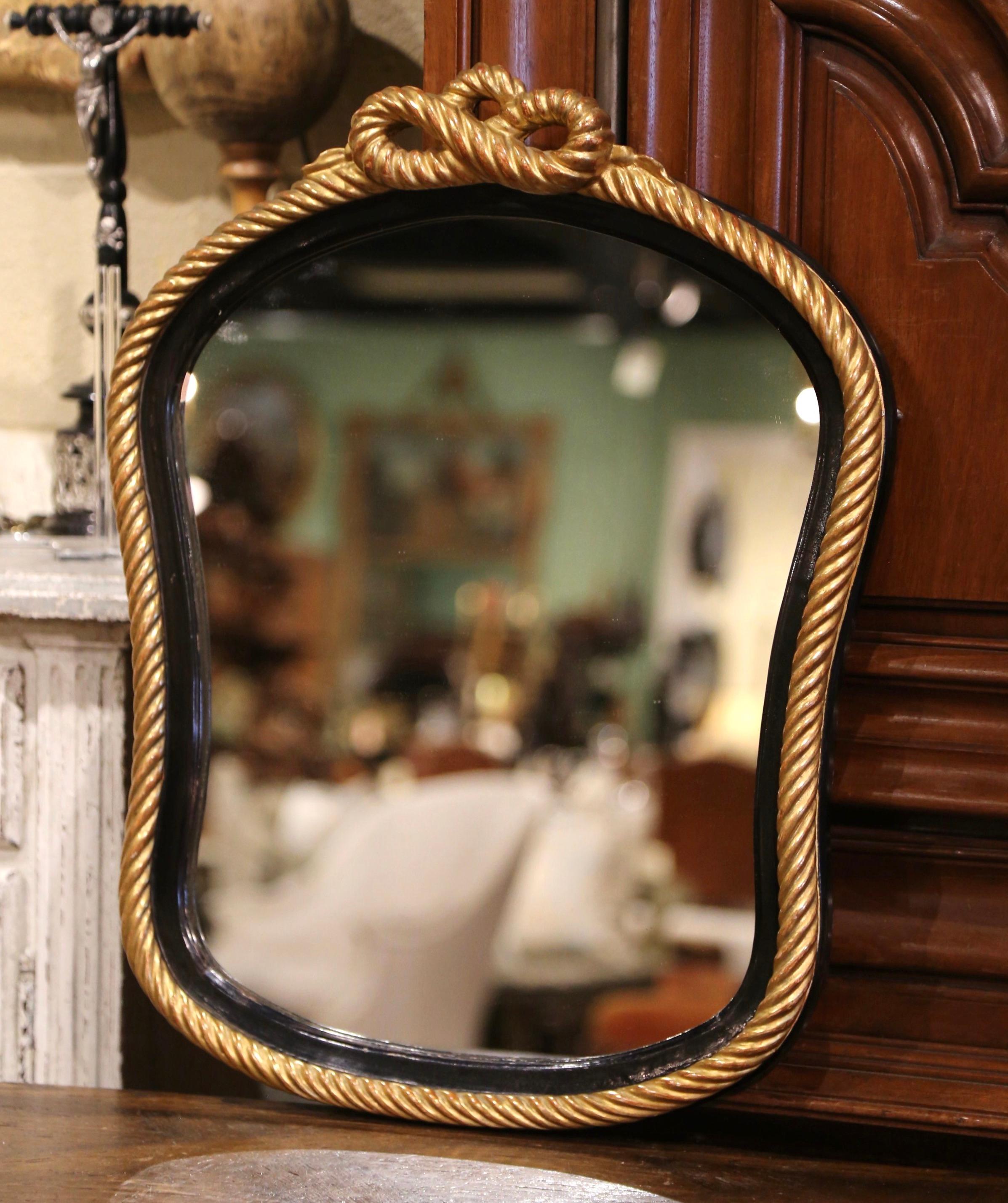 Decorate a powder room or entry way with this elegant antique two-tone mirror. Crafted in France, circa 1960, the shaped mirror features a blackened border decorated with a gold leaf rope form including a rope shape decor at the pediment. The frame