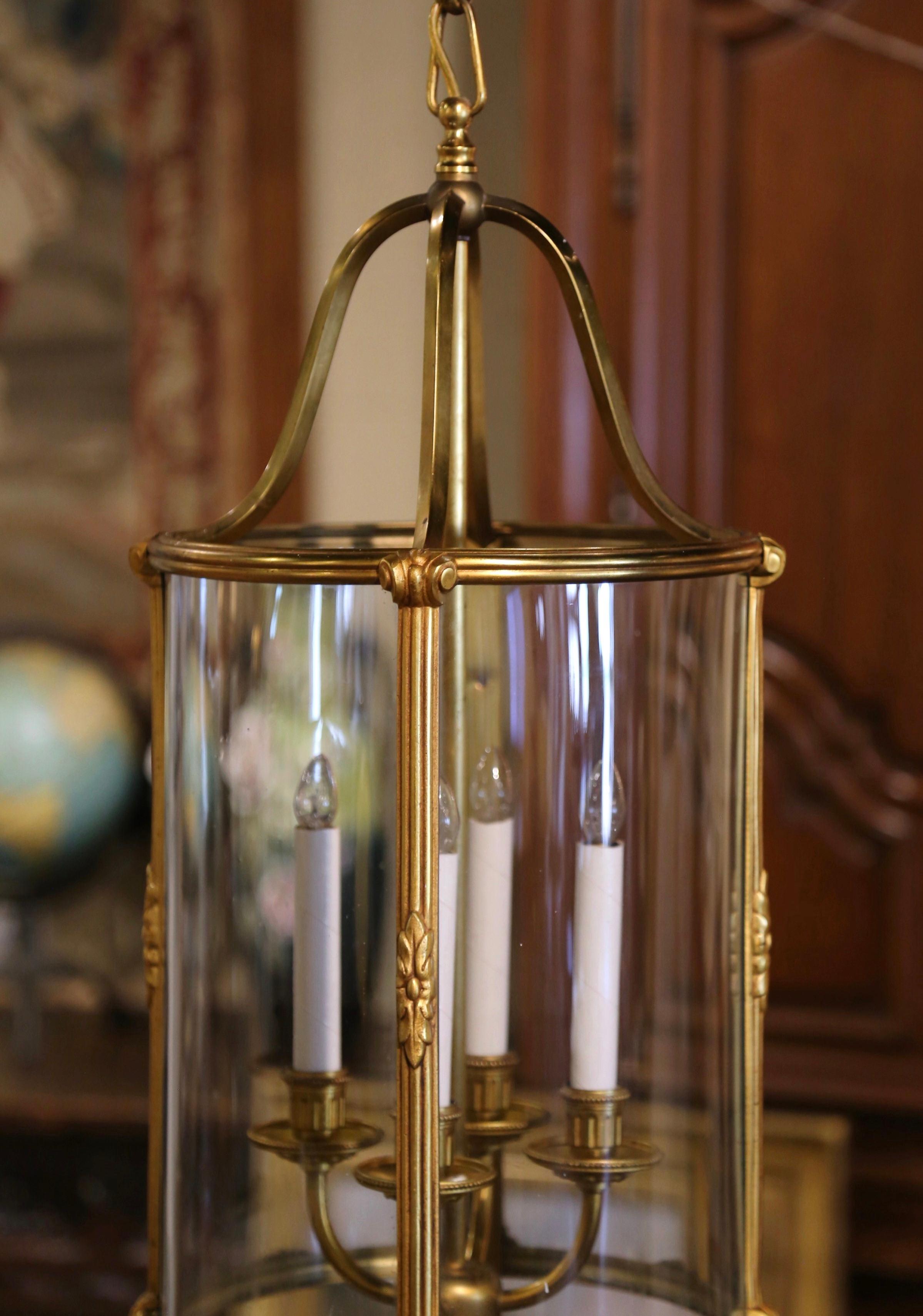 Illuminez votre entrée avec cette élégante lanterne en laiton ; fabriquée en France vers 1970, la haute lanterne ronde est ornée de quatre cloisons en laiton décorées de motifs de feuillage et se terminant par un fleuron central à la base. Cette