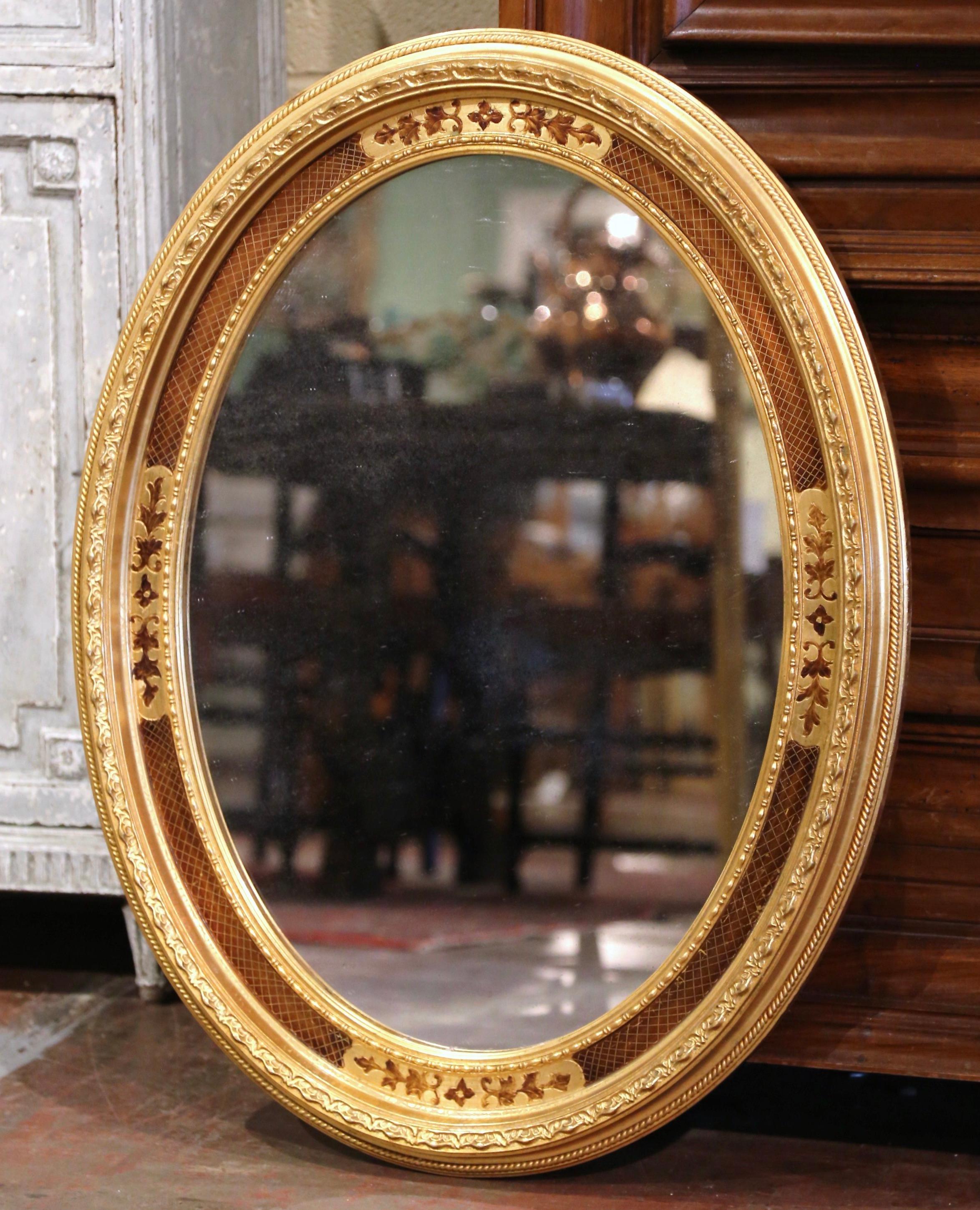 Decorate a powder room or entryway with this elegant antique wall mirror. Crafted in France, circa 1950, the oval frame is decorated with floral motifs and embellished with geometric motifs around the frame including bead decor. The Napoleon III