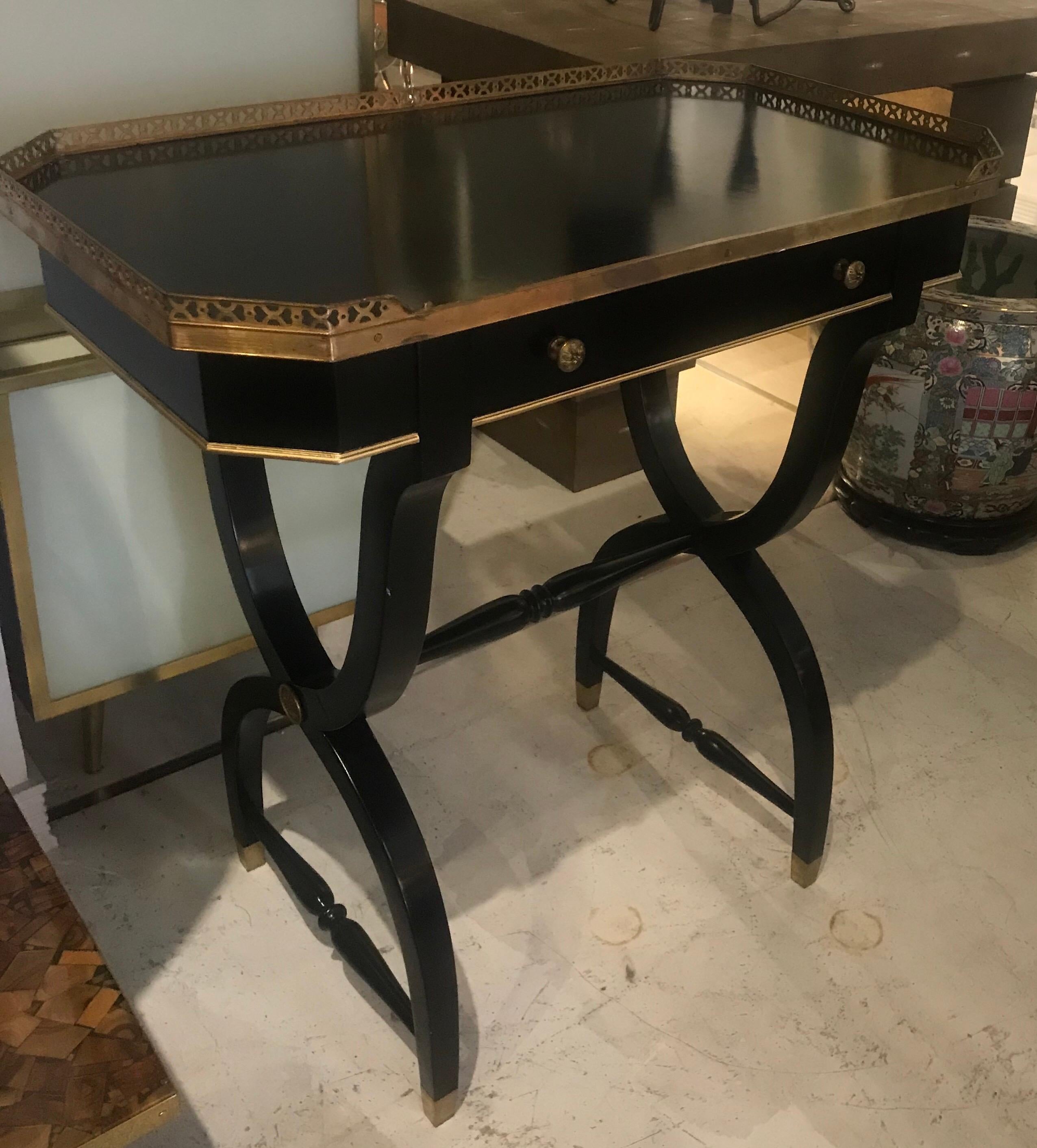 A stunning midcentury French neoclassical writing desk or console of beautiful ebonized wood with bronze trim and details. This neoclassical console table or writing desk have Curule style legs with an ebonized finish and decorative floral mounts,