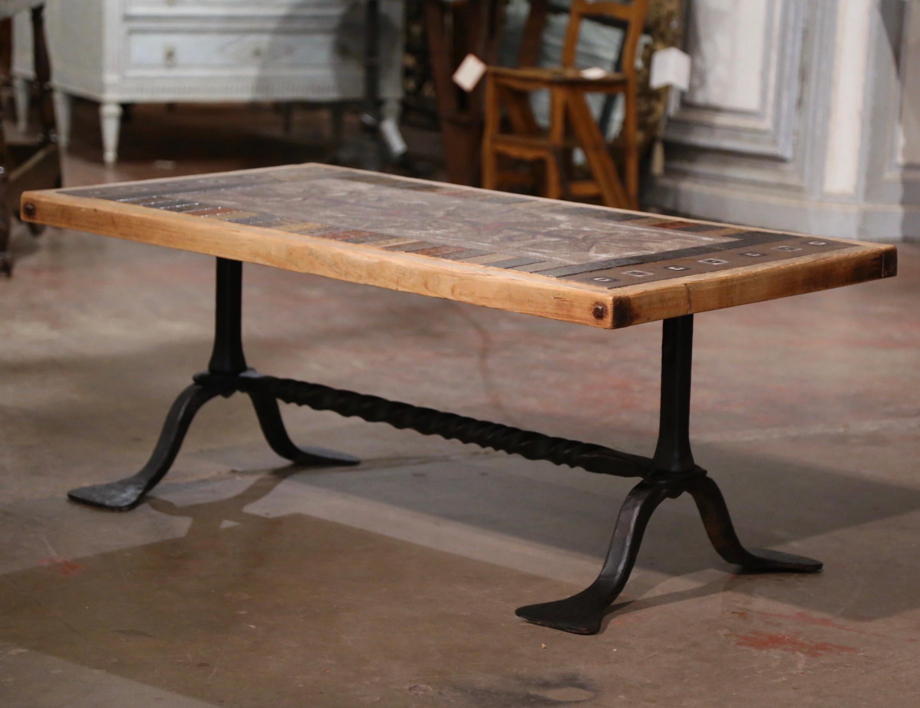 Decorate a den or a living room with this elegant antique cocktail table. Crafted in Vallauris, southern France circa 1950, the low table stands on a forged wrought iron trestle base. The rectangular top, signed by the artist J.G. Picard, is built