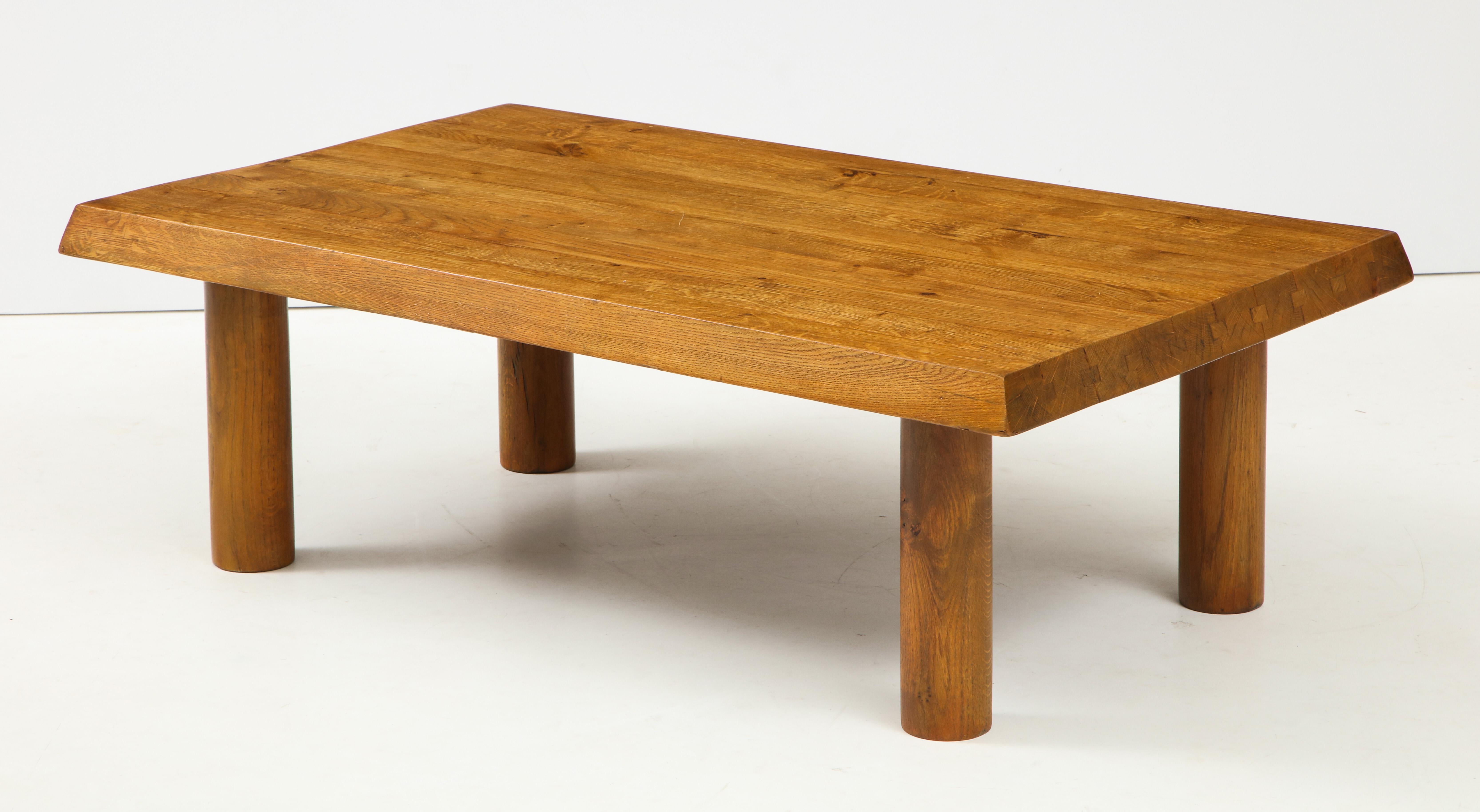 This coffee table was designed in the 1950s and 1960s in France under the inspiration of Charlotte Perriand or Pierre Chapo. Crafted in solid oak, it is composed of four cylindrical feet and a thick rectangular top, assembly by tongues and grooves