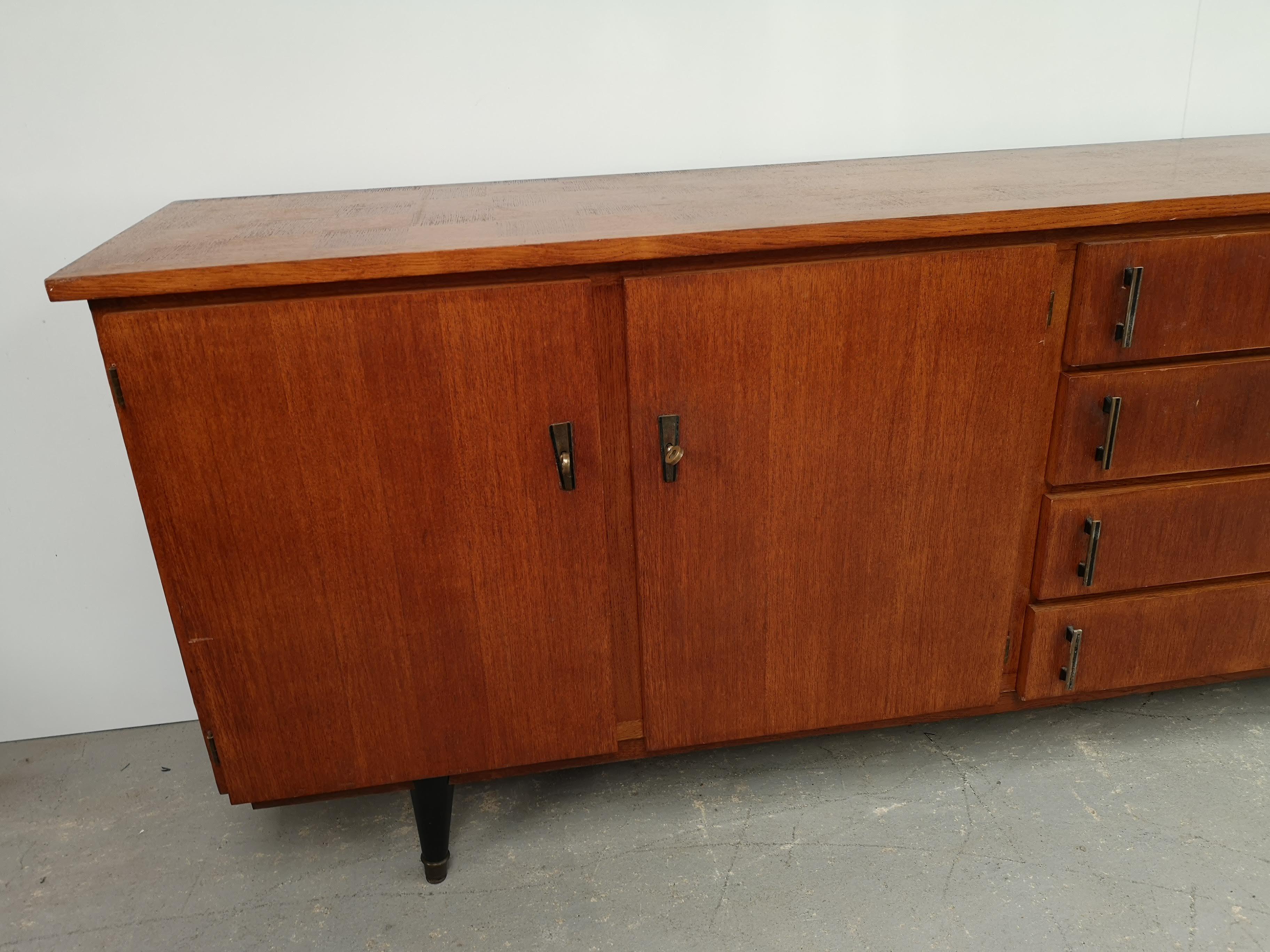 A vintage oak sideboard, its metal handles are design.
In the middle: four drawers of different heights provide storage.
On the left: two doors open onto a section with two shelves for storing crockery and accessories.
On the right: an overhead