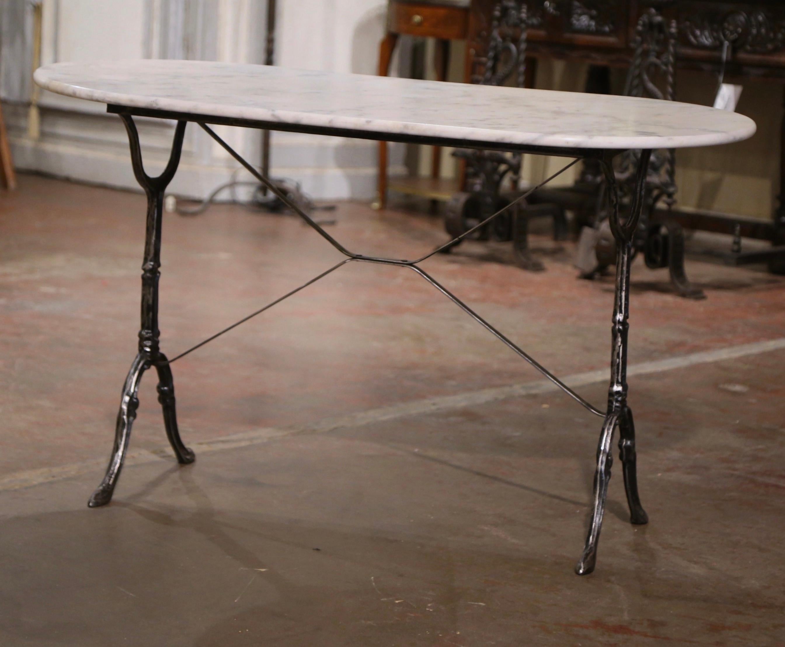 Decorate a patio or covered porch with this elegant antique bistrot table. Crafted in France circa 1960, the cast iron table sits on a trestle base with elegant scroll legs ending with hoof feet, and joined together with a double decorative crossed