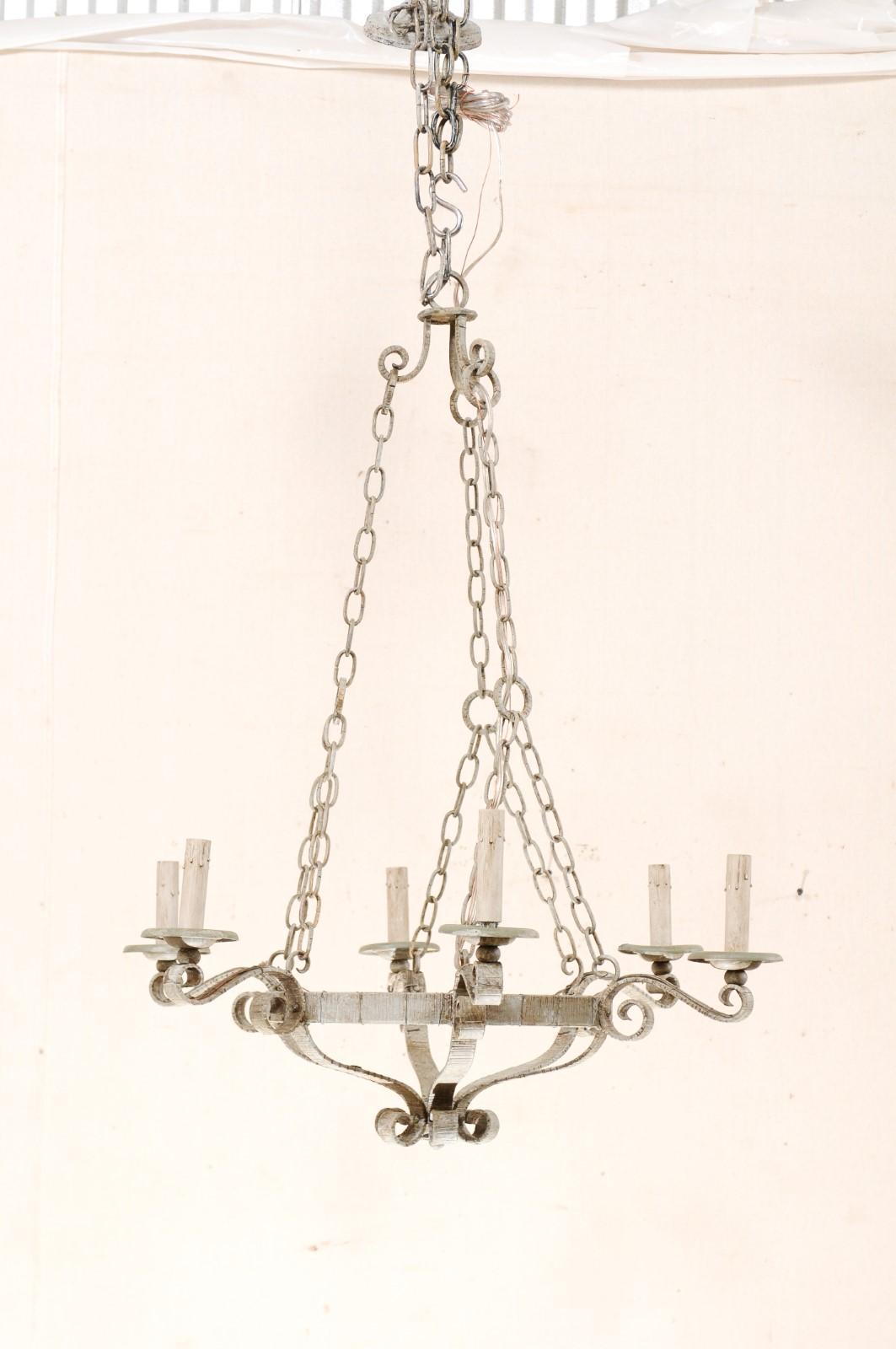 A French six-light painted iron chandelier from the mid-20th century. This vintage painted iron chandelier from France features a textured central ring with a shallow-basket design with scrolling accents at the bottom of the light. Six S-scroll arms