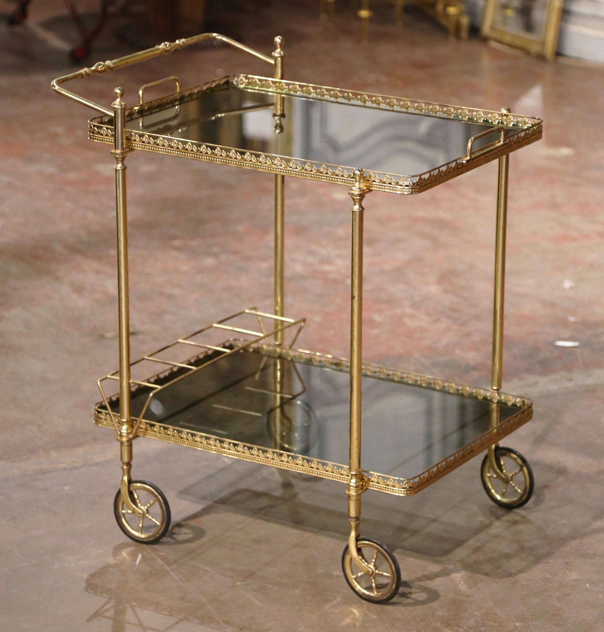 This elegant vintage rolling bar cart was created in France, circa 1960. Built in brass a with a rectangle shape, the two-tier dessert trolley stands on small round wheels with rubber tires, over two plateau topped tinted glass surfaces. The top