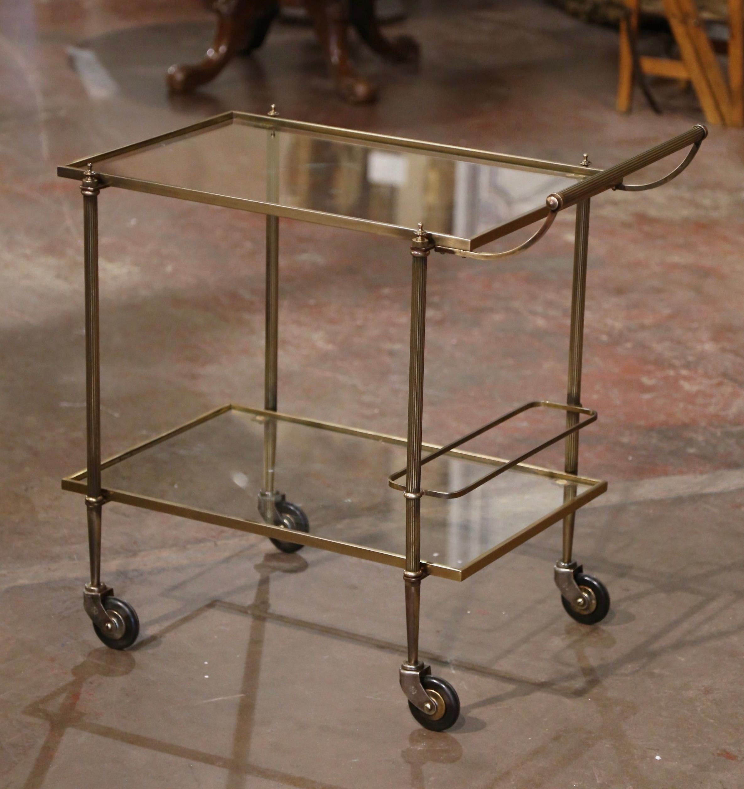 This elegant vintage rolling bar cart was created in France, circa 1960. Built in brass a with a rectangle shape, the two-tier dessert trolley stands on small round wheels with rubber tires, and two glass surfaces. The top deck features a