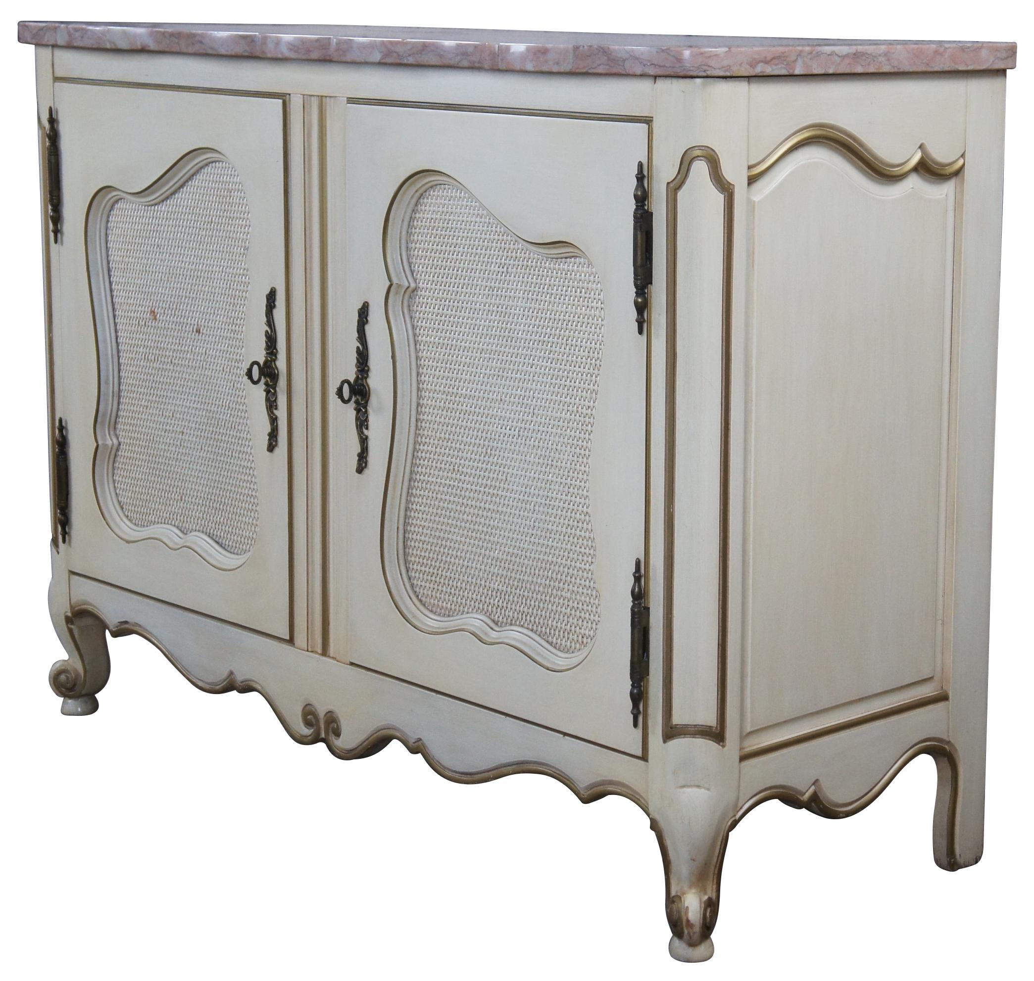 French Provincial console or cabinet, circa 1959. Features a serpentine pink marble top over rectangular base of two doors with inset rattan backing and cabriole scrolled feet. The cabinet is enhanced by shapely molding trimmed in gold and scrolling